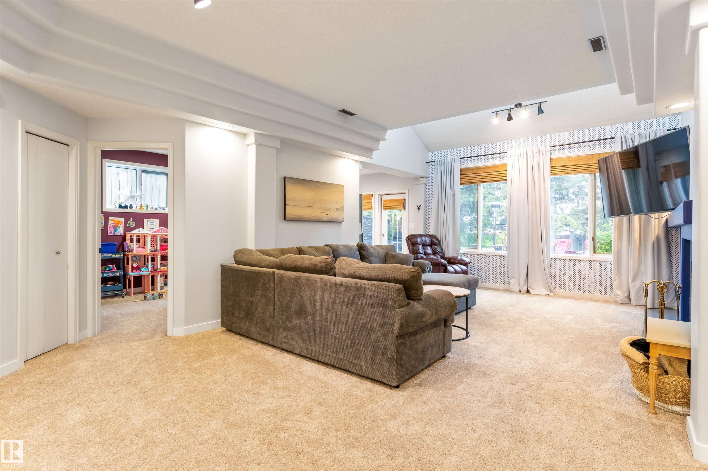 Spacious living area featuring light-colored carpeting and vaulted ceilings with recessed lighting - 10 Everest Crescent, St. Albert, AB