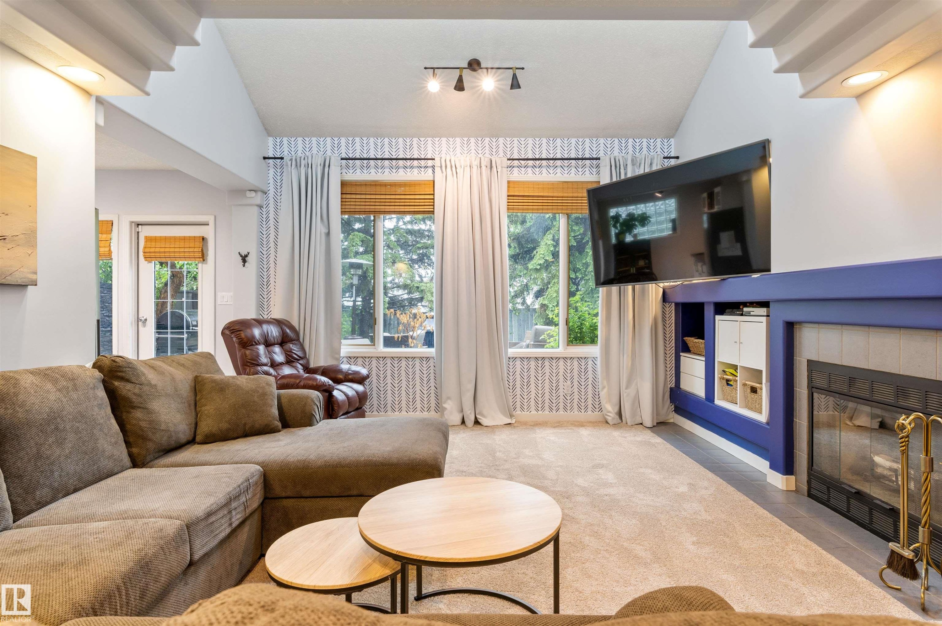 Living room featuring a fireplace with a blue mantel, built-in shelving, vaulted ceilings, and large windows - 10 Everest Crescent, St. Albert, AB