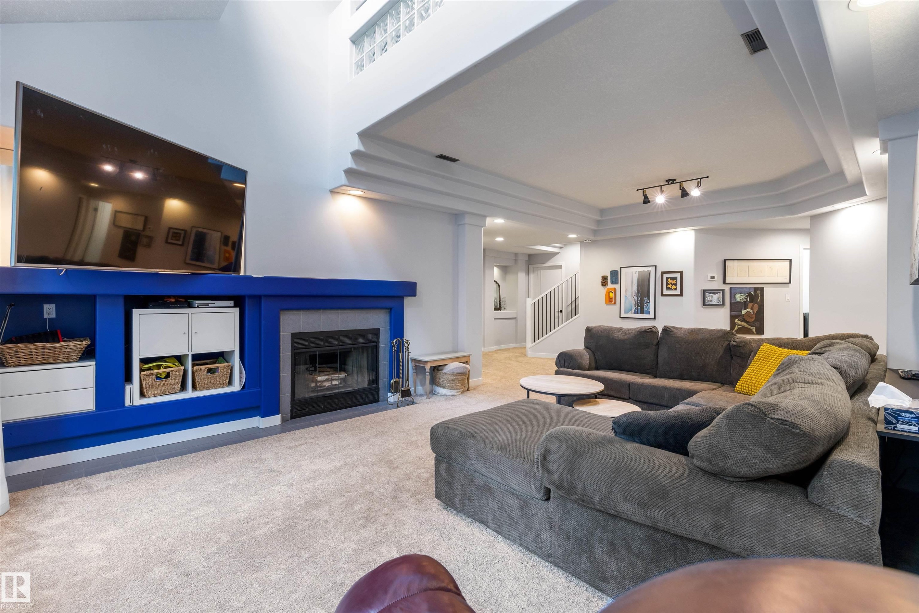 Living area featuring a floor-to-ceiling fireplace with tile surround, built-in shelving, and a tray ceiling - 10 Everest Crescent, St. Albert, AB