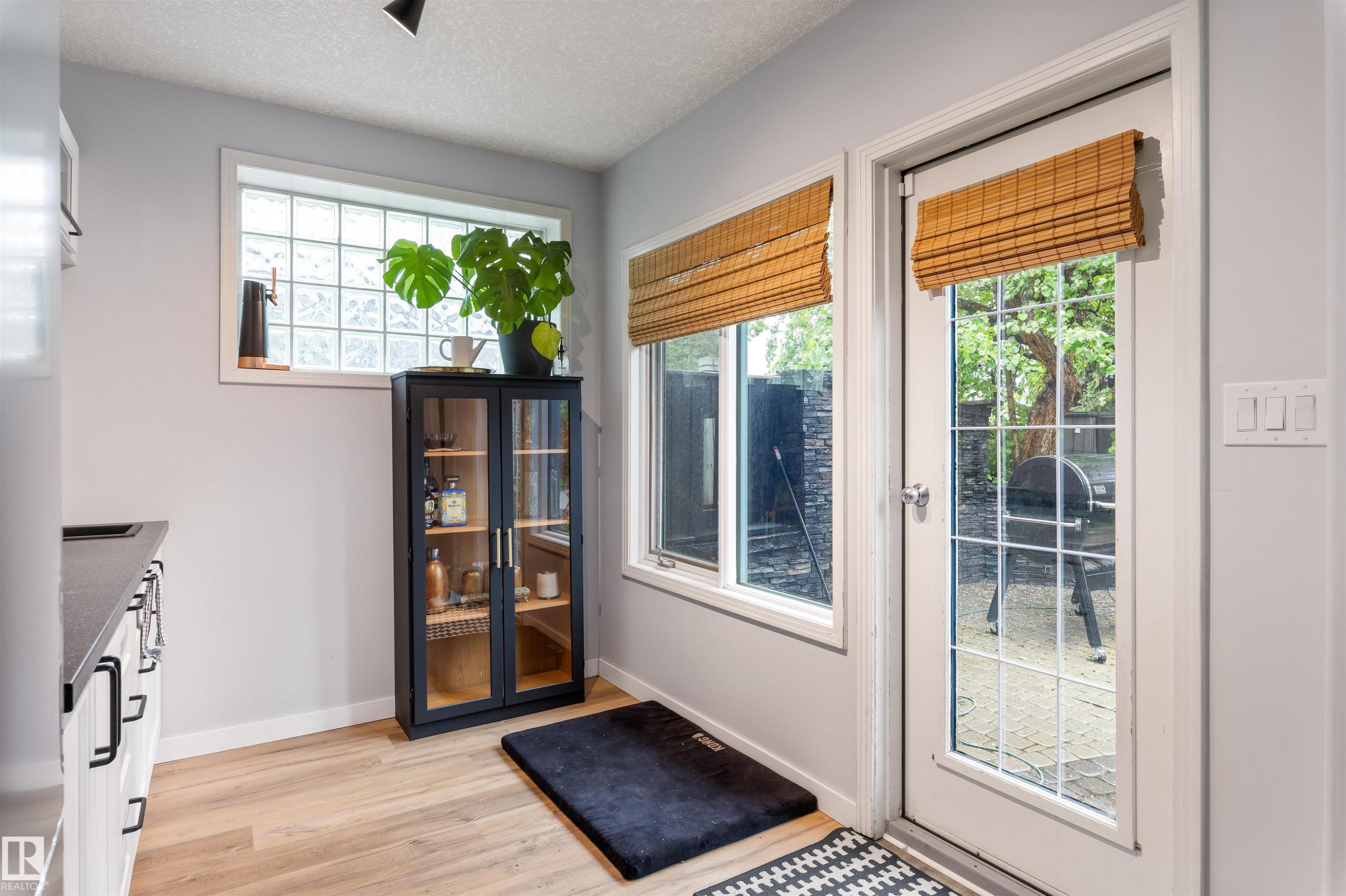Glass-paned patio door with a coordinating side window, each featuring natural woven shades - 10 Everest Crescent, St. Albert, AB