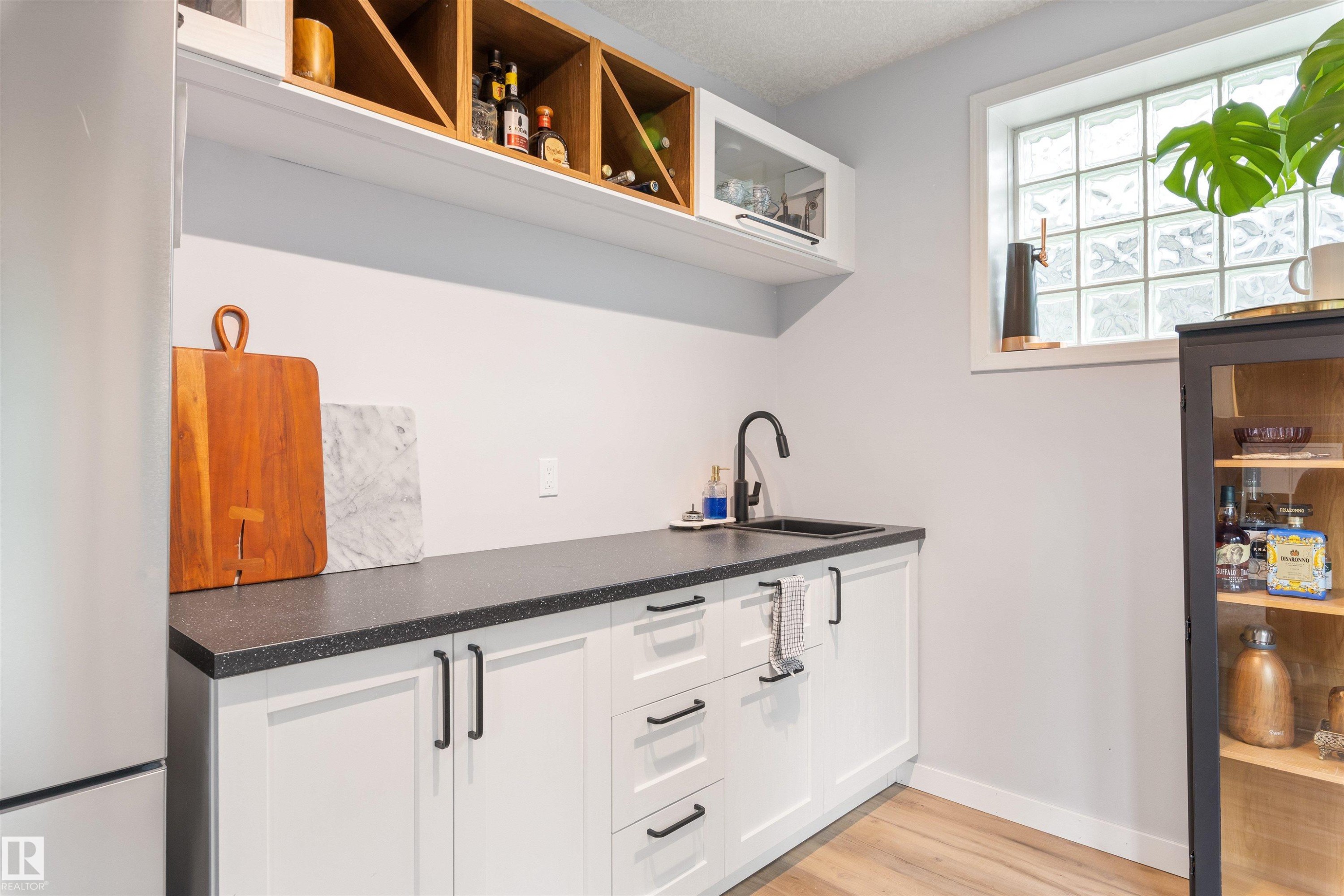 Wet bar featuring white shaker-style cabinetry, black countertops, a matte black faucet, and a black undermount sink - 10 Everest Crescent, St. Albert, AB
