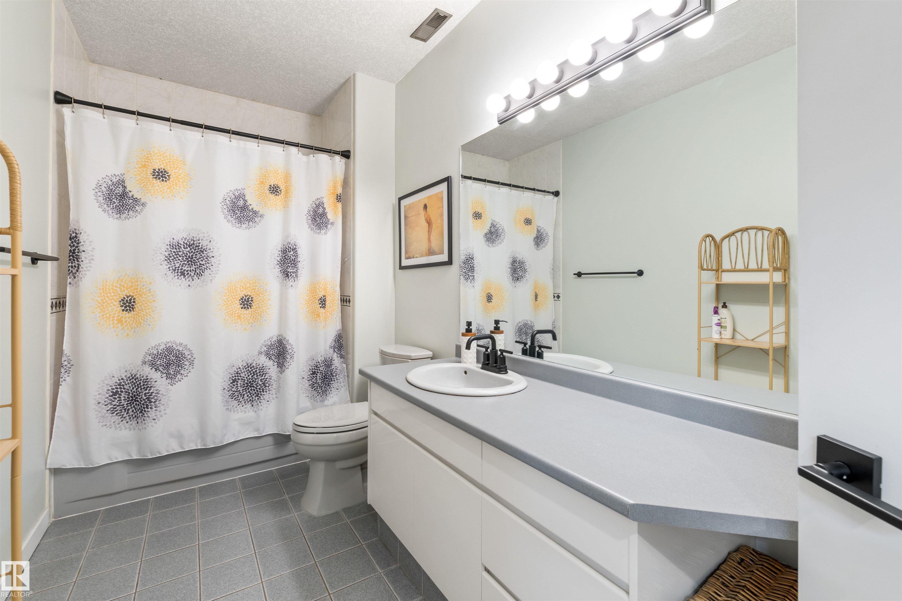 Bathroom featuring a single basin vanity with a light gray countertop, matte black faucet, and a large wall-mounted mirror - 10 Everest Crescent, St. Albert, AB