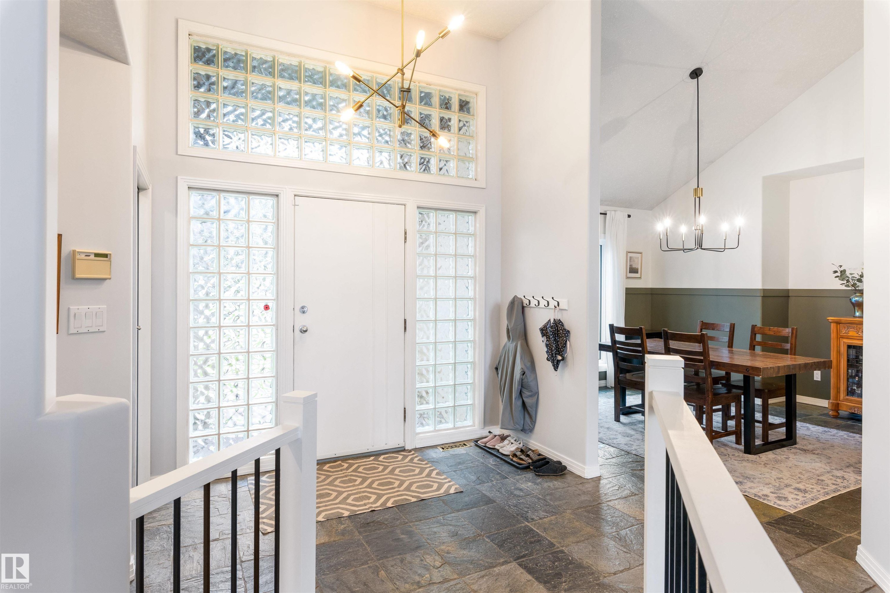 Entryway featuring stone-finish flooring, a white door with glass block sidelights, and a transom window with glass blocks - 10 Everest Crescent, St. Albert, AB