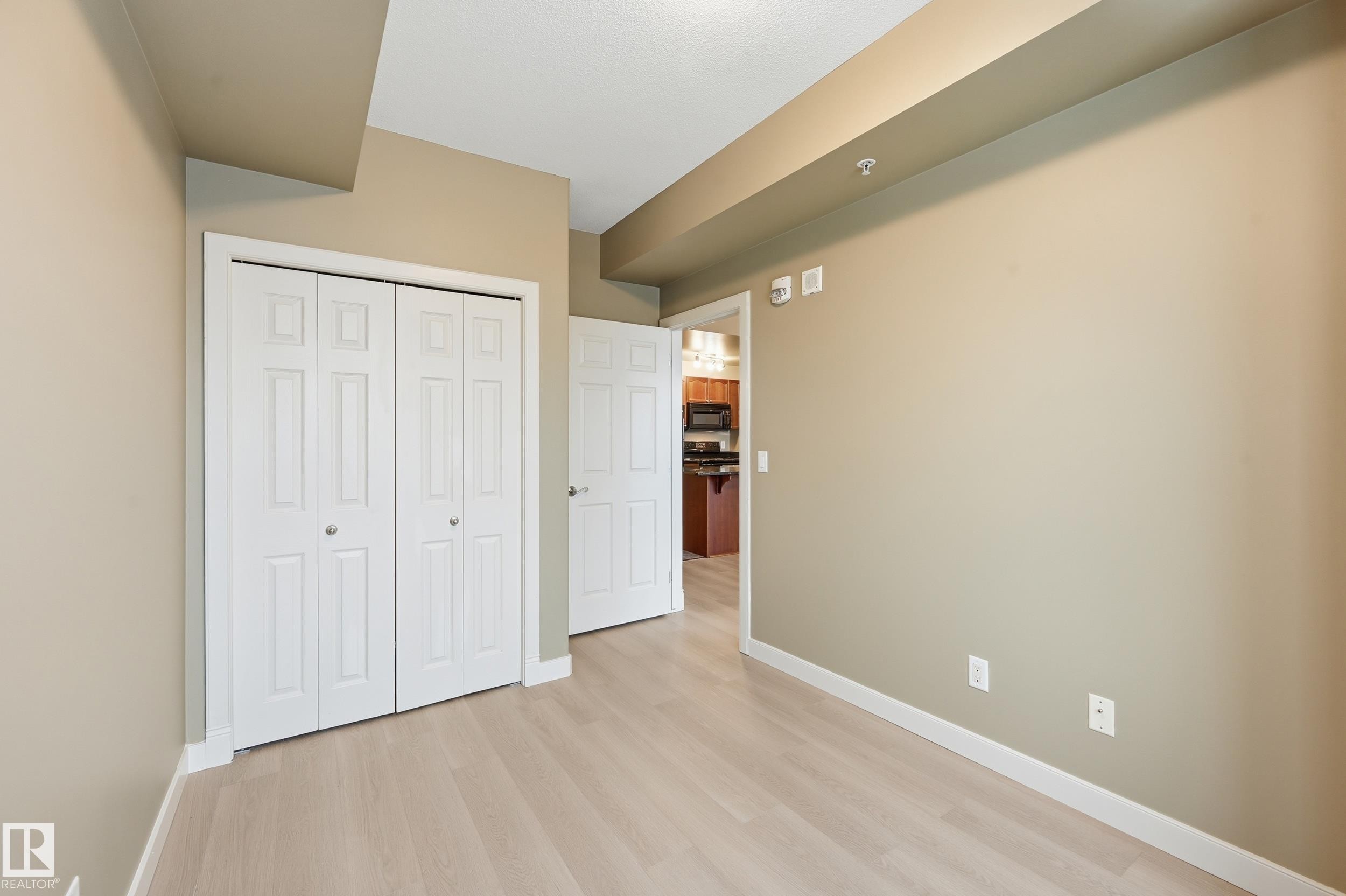 Light wood-finish flooring with neutral wall tones - #1407 9939 109 St Nw, Edmonton, AB