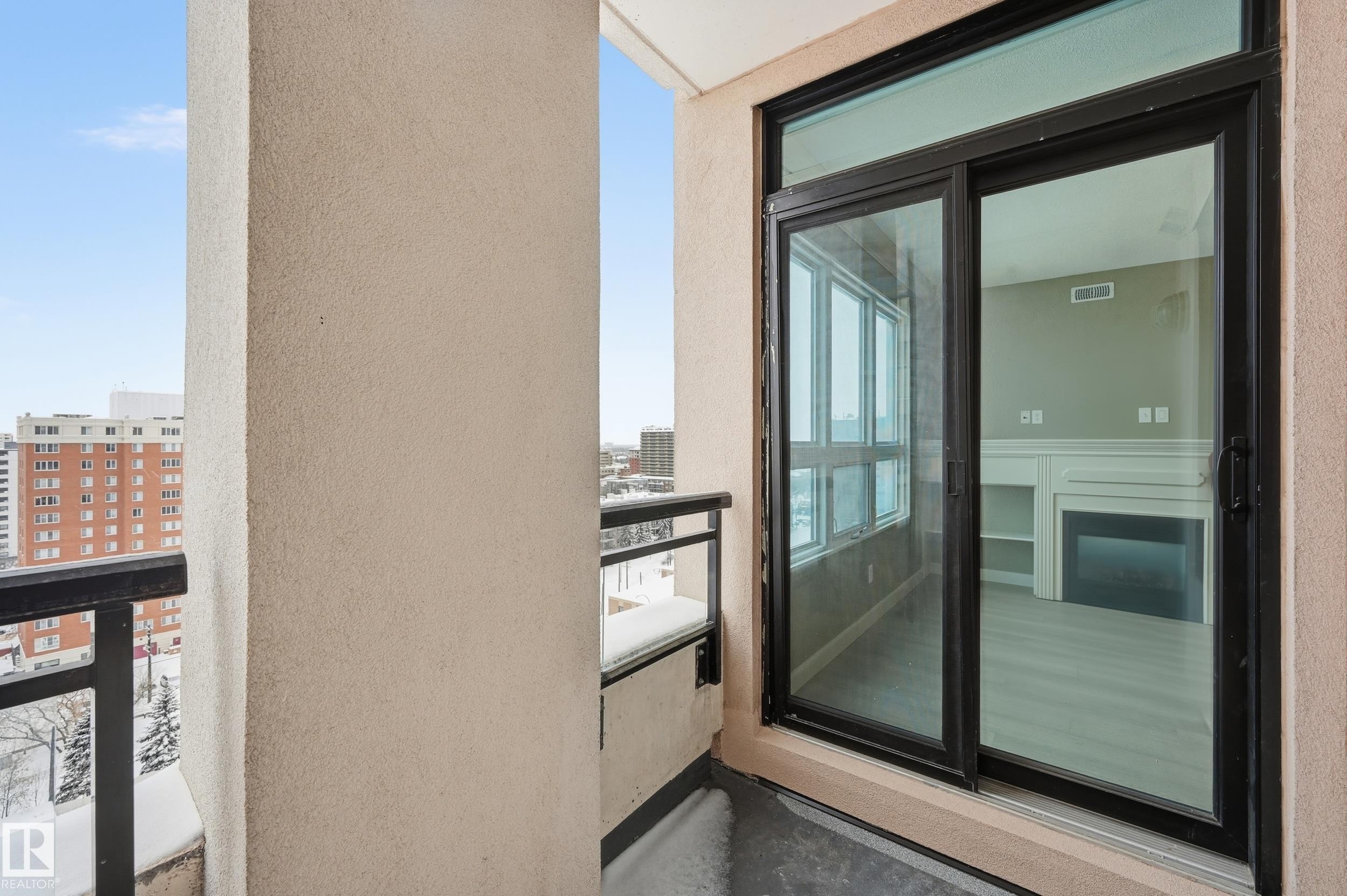 Outdoor balcony with a stucco finish, black metal railing, and a sliding glass door - #1407 9939 109 St Nw, Edmonton, AB