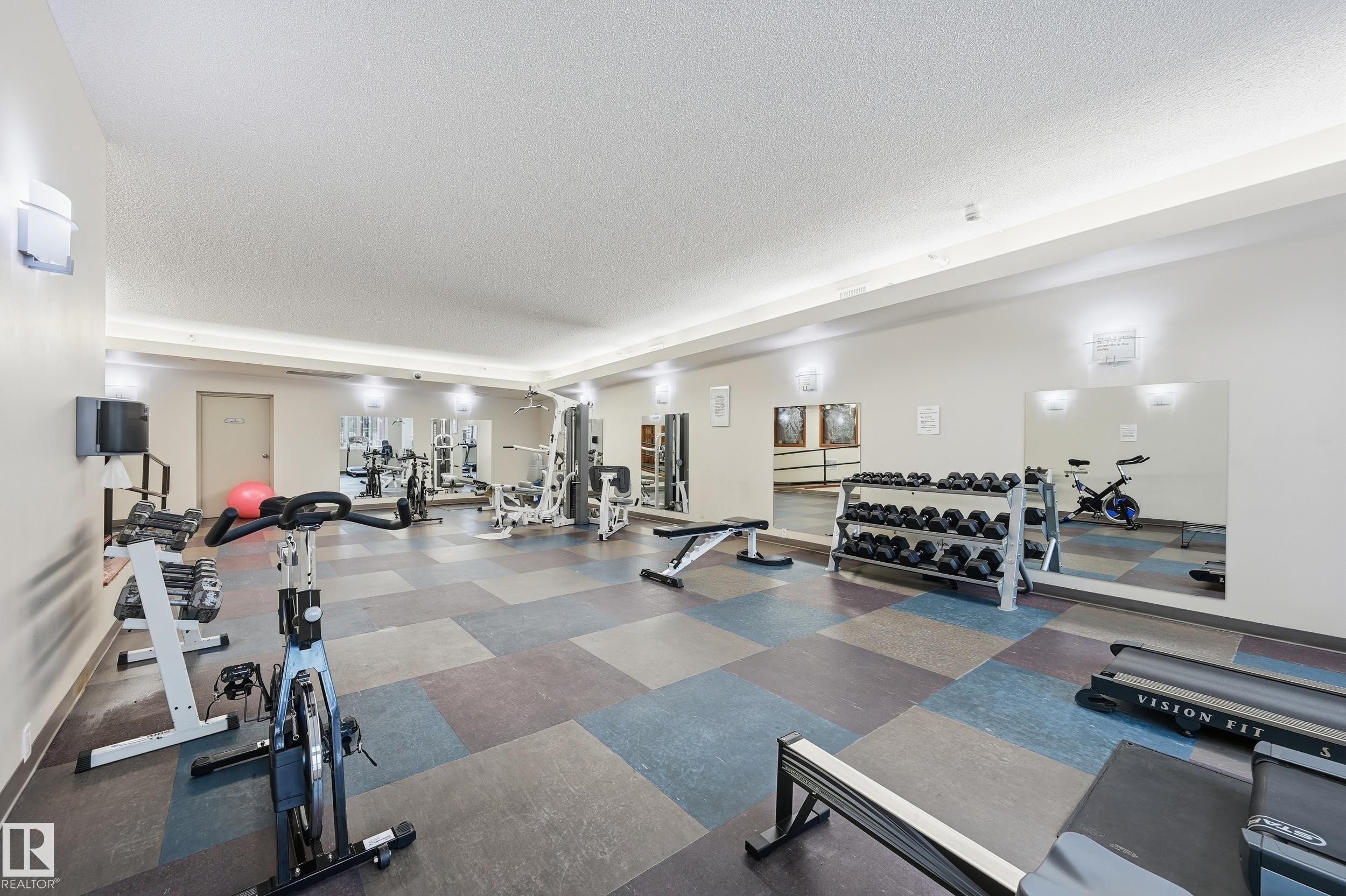 Fitness room featuring a variety of exercise equipment, wall-mounted mirrors, and recessed lighting - #1407 9939 109 St Nw, Edmonton, AB