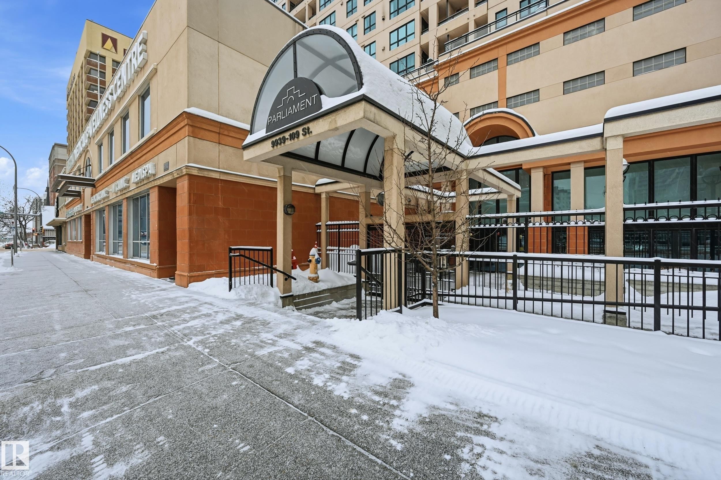 Building exterior featuring a covered entrance with an arched canopy, a stone facade, and large windows - #1407 9939 109 St Nw, Edmonton, AB