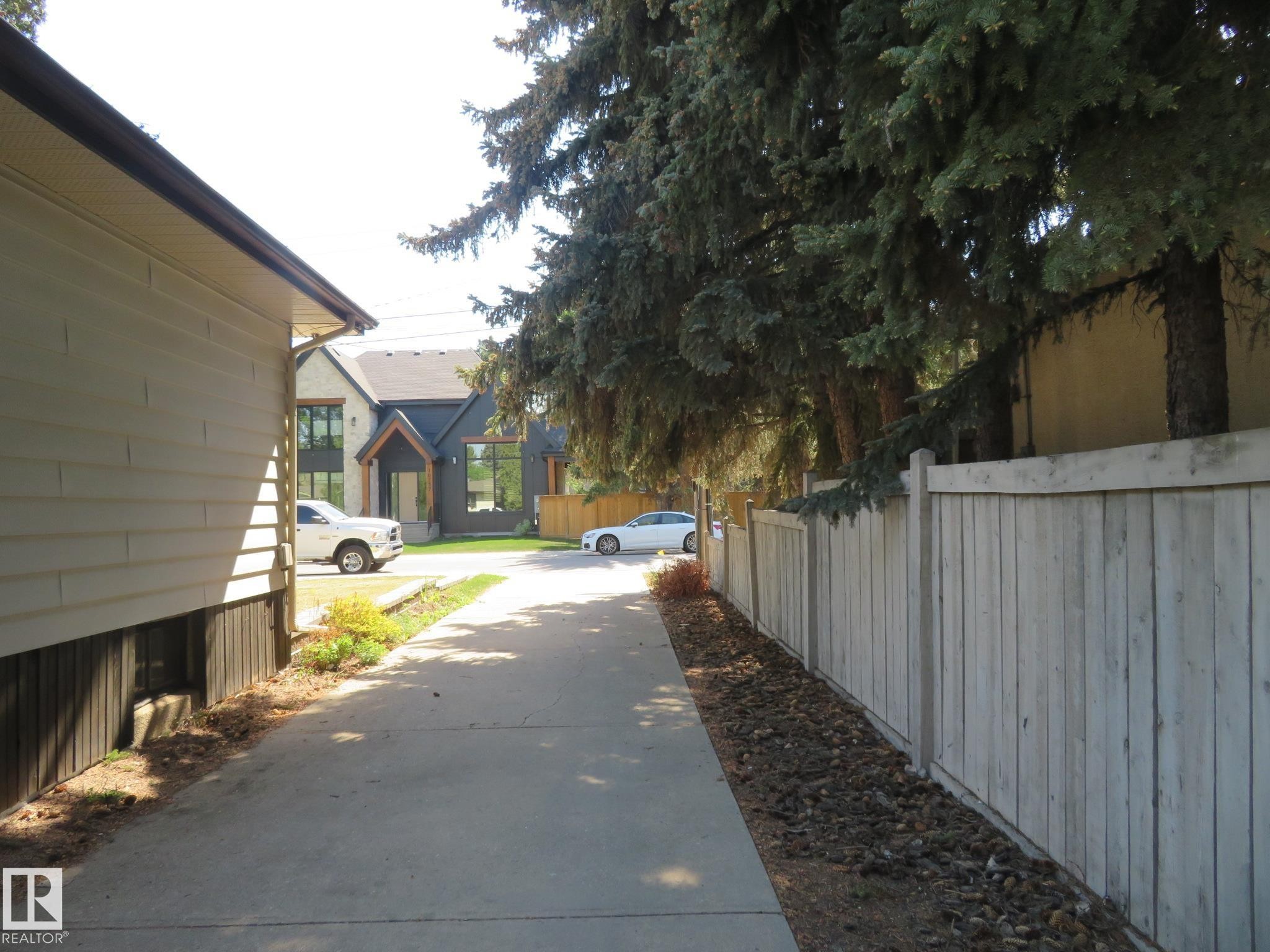 Concrete driveway with a wood fence and mature trees - 10720 57 Avenue Nw, Edmonton, AB - Outdoor
