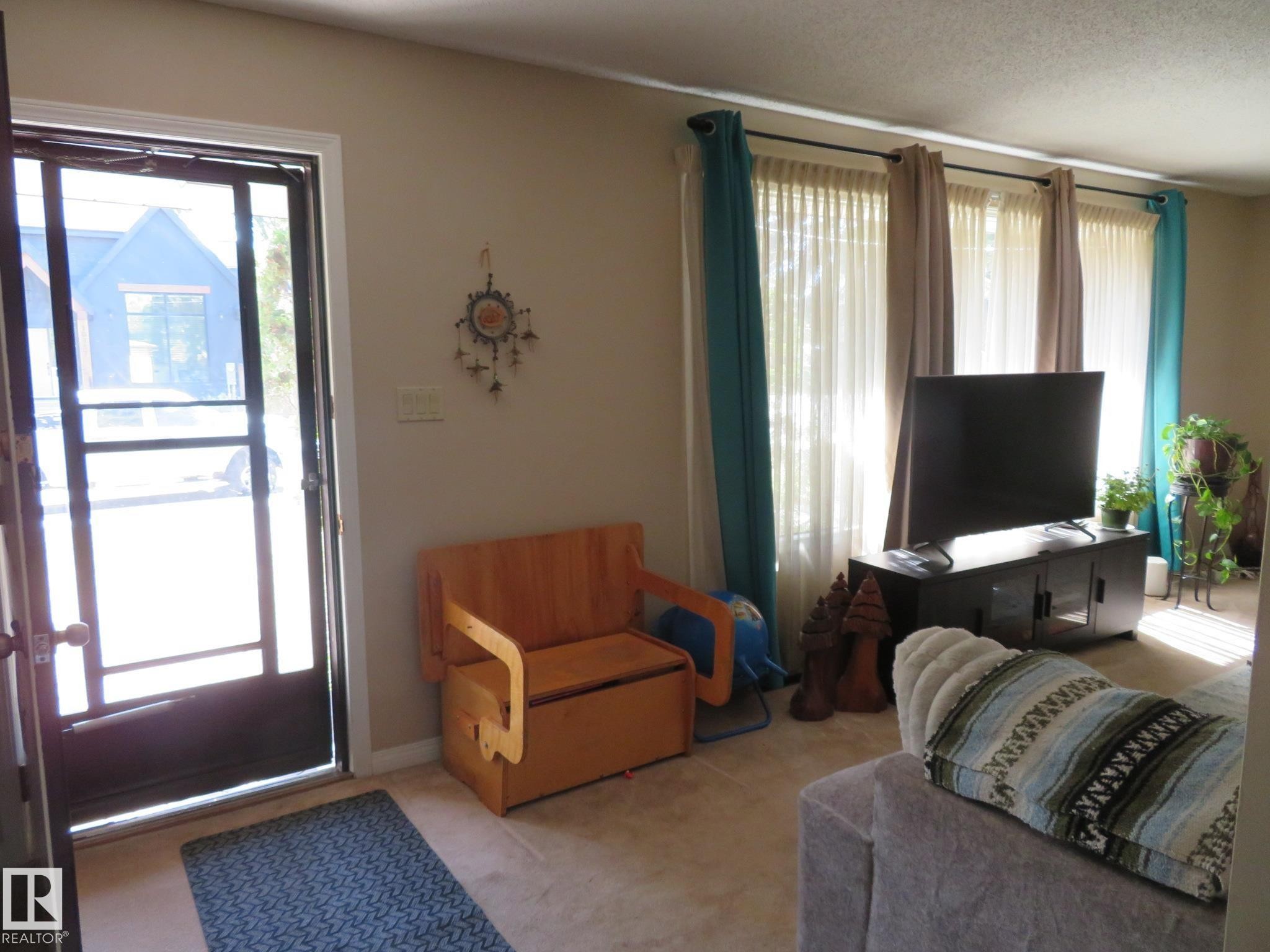 Living area featuring a full-light storm door and triple windows - 10720 57 Avenue Nw, Edmonton, AB - Indoor