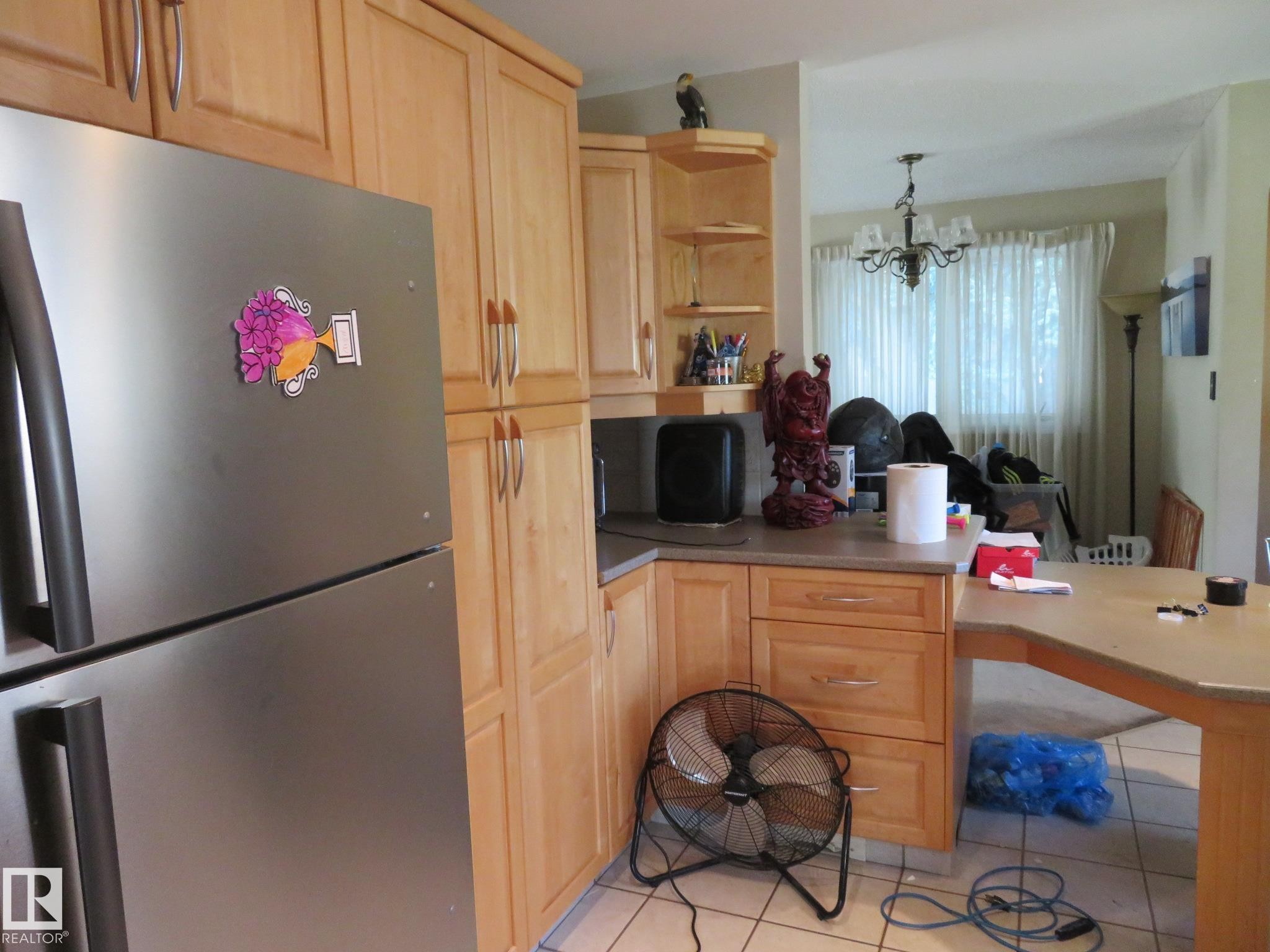 Kitchen featuring natural wood-finish cabinetry, stainless steel refrigerator, and tiled flooring - 10720 57 Avenue Nw, Edmonton, AB - Indoor