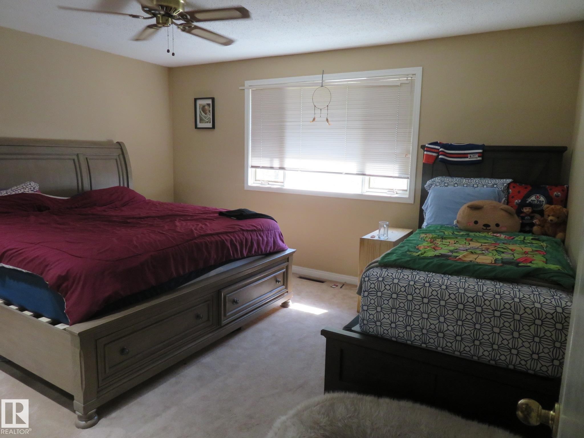 Carpeted room featuring a ceiling fan with light, a window with blinds, and neutral-toned wall paint - 10720 57 Avenue Nw, Edmonton, AB - Indoor Photo Showing Bedroom