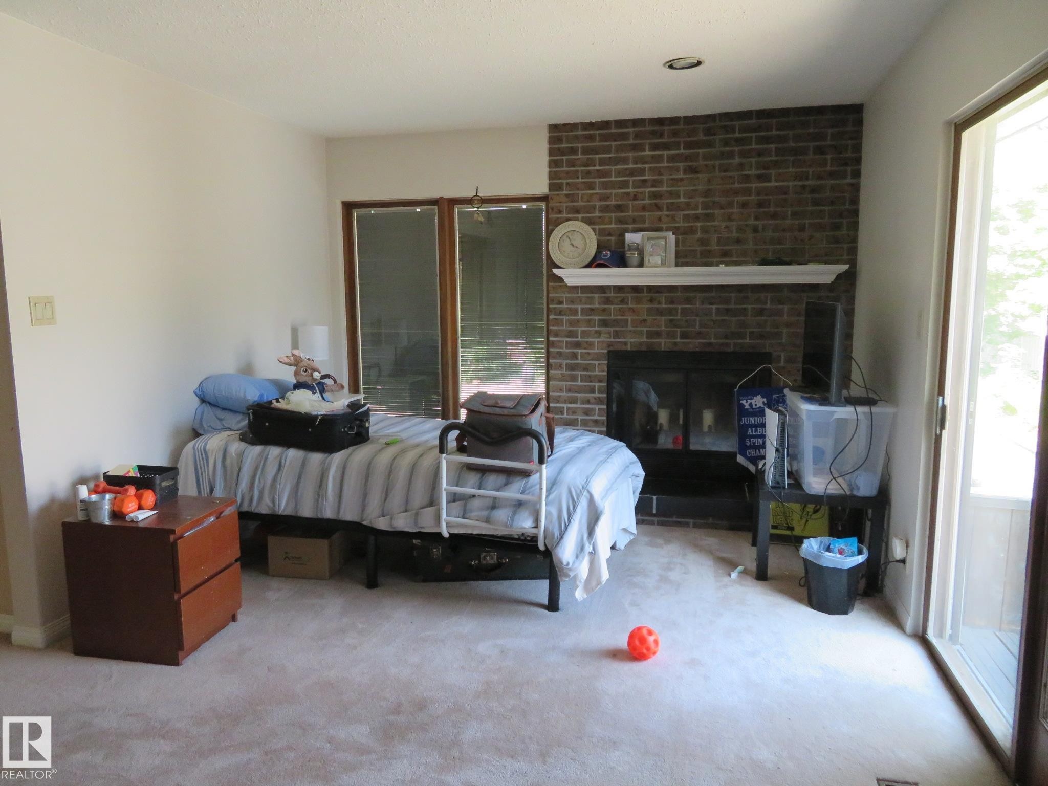Living area featuring a brick fireplace with a white mantel, sliding glass doors, and recessed lighting - 10720 57 Avenue Nw, Edmonton, AB - Indoor With Fireplace