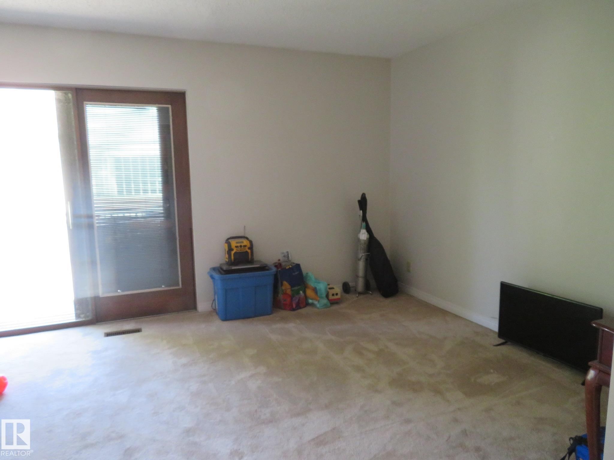 Carpeted room with a sliding glass door featuring a wood-finish frame - 10720 57 Avenue Nw, Edmonton, AB - Indoor Photo Showing Other Room