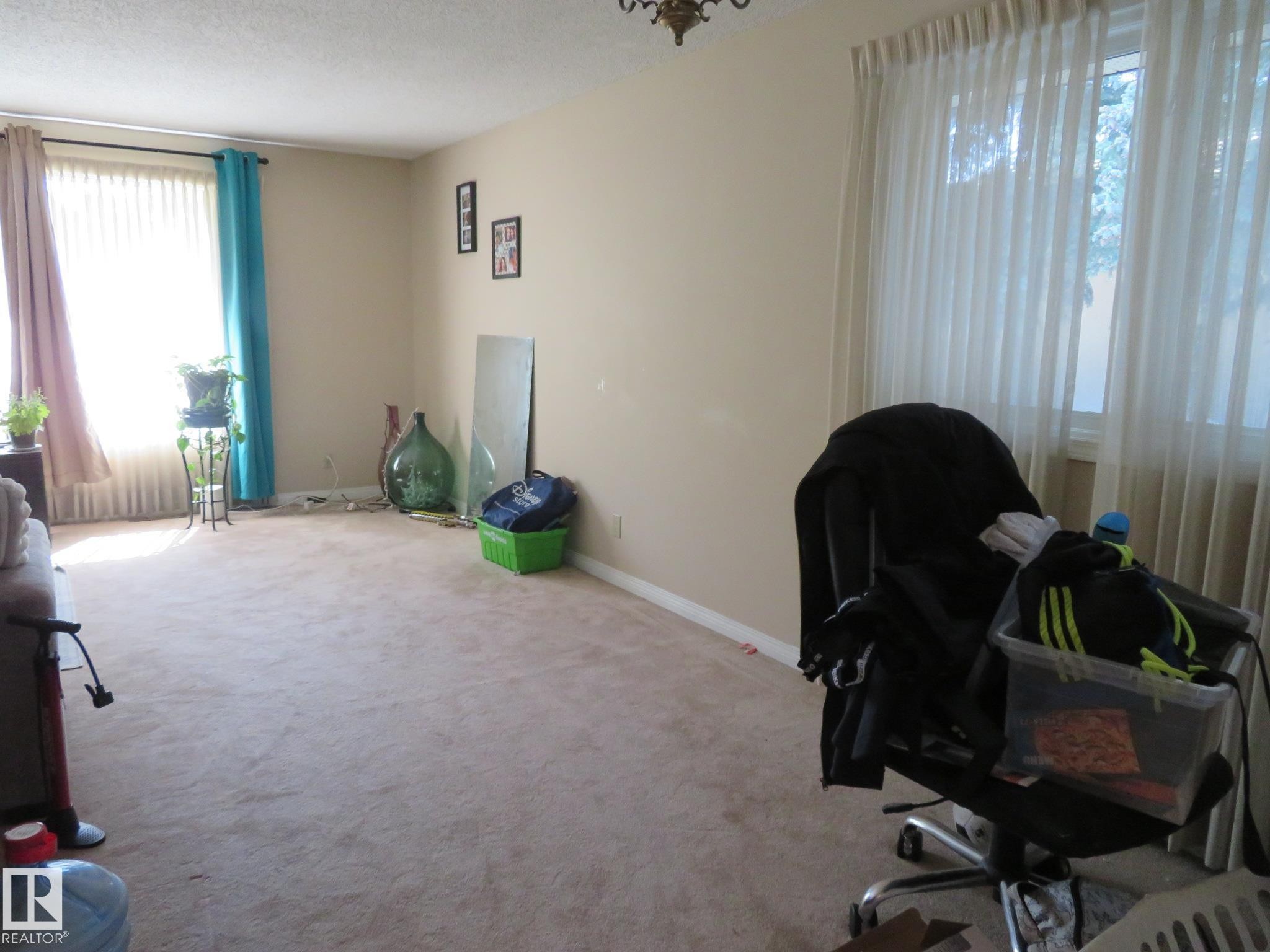 Carpeted room with neutral wall paint and two large windows - 10720 57 Avenue Nw, Edmonton, AB - Indoor