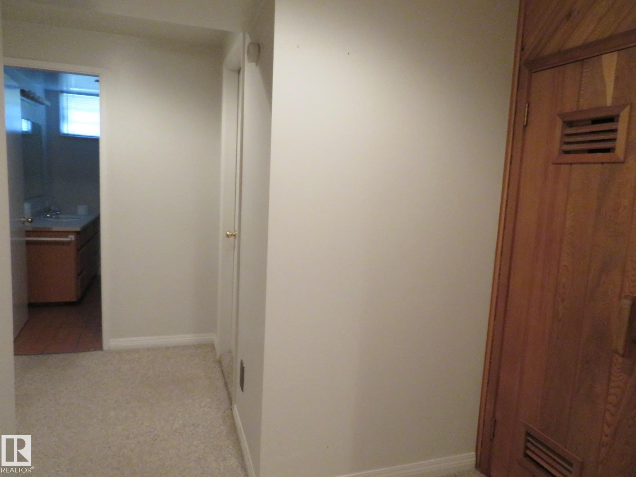 Hallway with light-colored carpet flooring and white baseboards - 10720 57 Avenue Nw, Edmonton, AB - Indoor