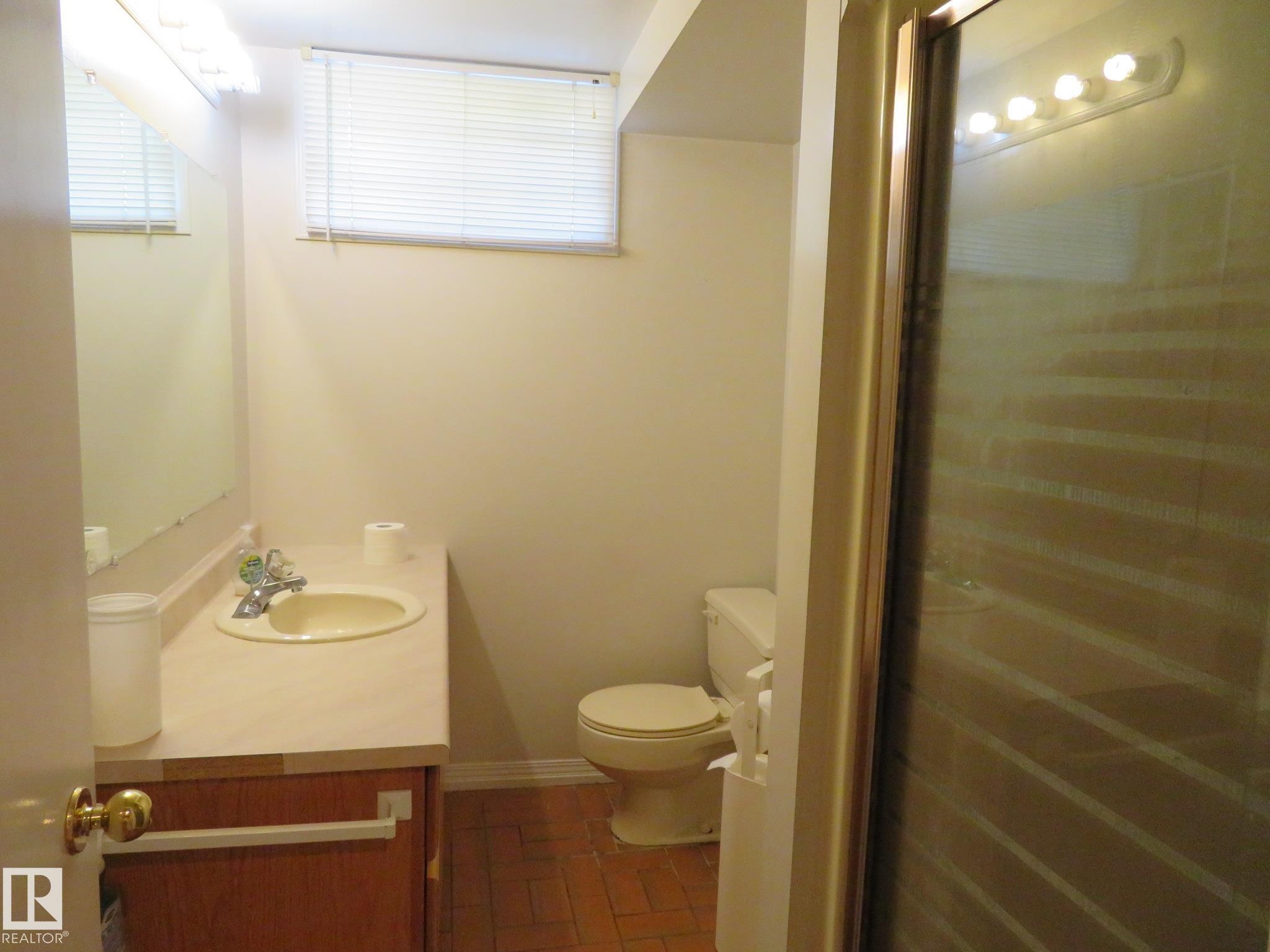 Bathroom featuring a vanity with an integrated sink, mirror, and toilet - 10720 57 Avenue Nw, Edmonton, AB - Indoor Photo Showing Bathroom