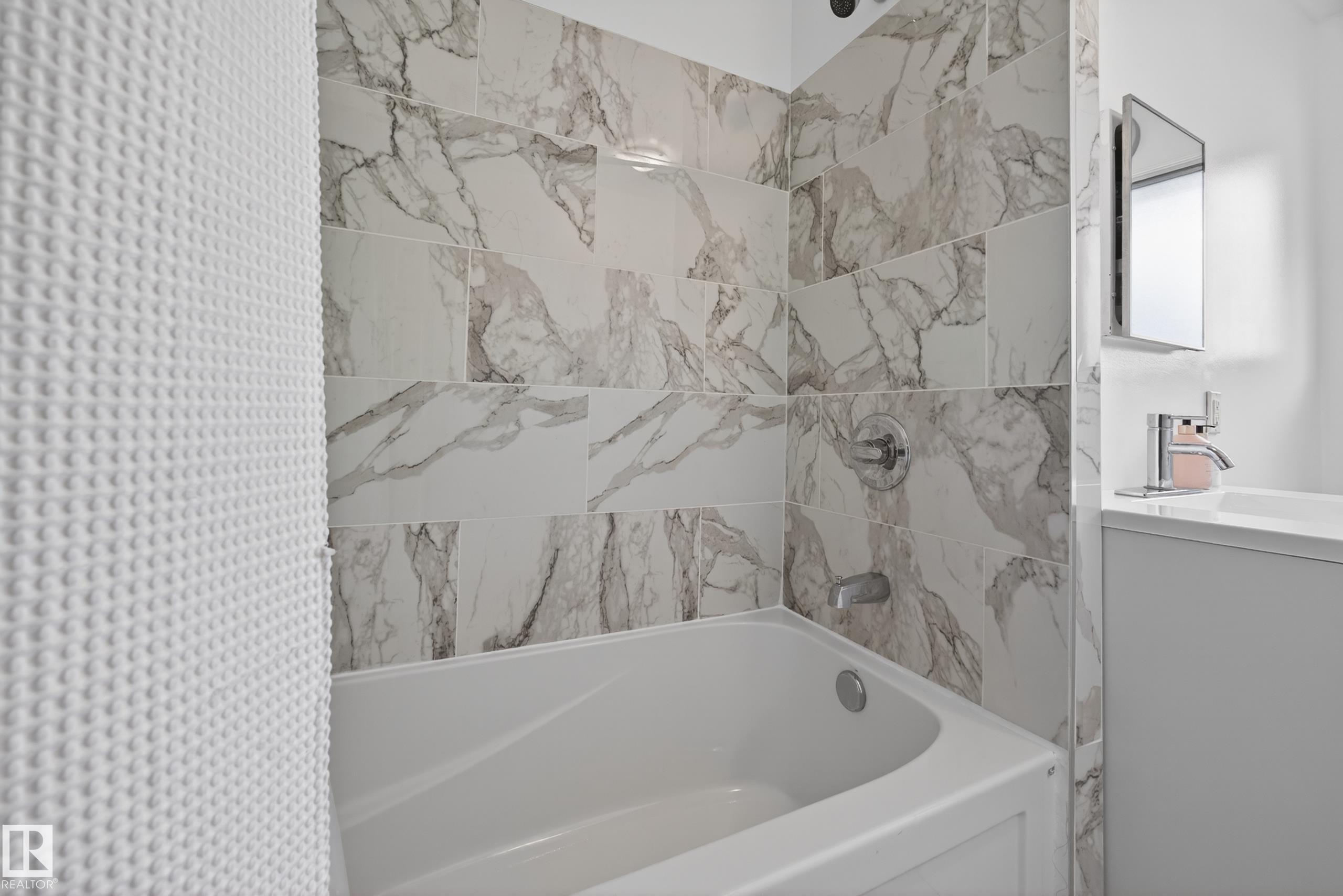 Tub and shower combination featuring large format marble-look wall tiles, chrome fixtures, and a white soaking tub - 5216 104A Street, Edmonton, AB - Indoor Photo Showing Bathroom
