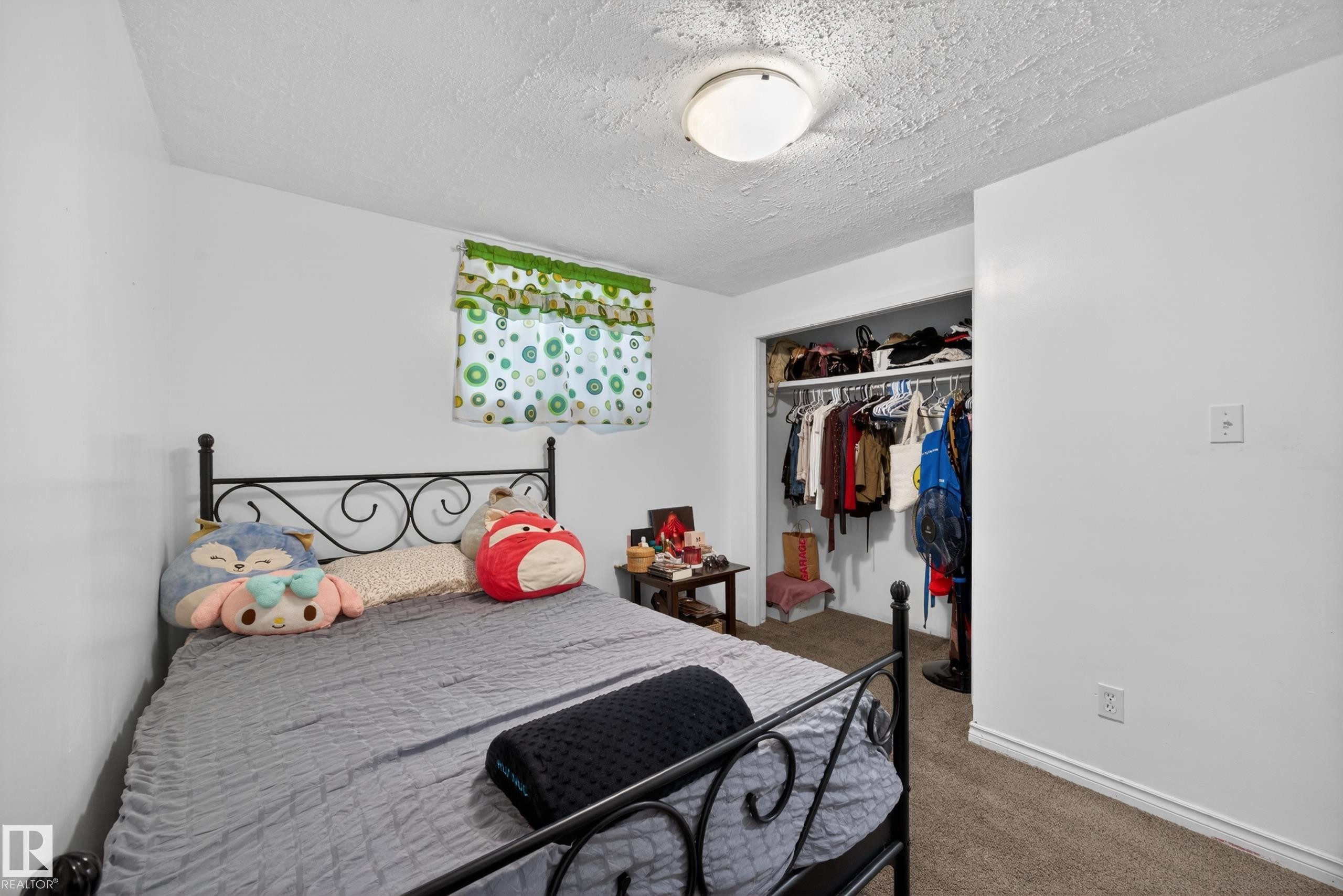 Carpeted bedroom featuring white walls, a single window with a valance, and an open closet with shelving and hanging space - 5216 104A Street, Edmonton, AB - Indoor Photo Showing Bedroom
