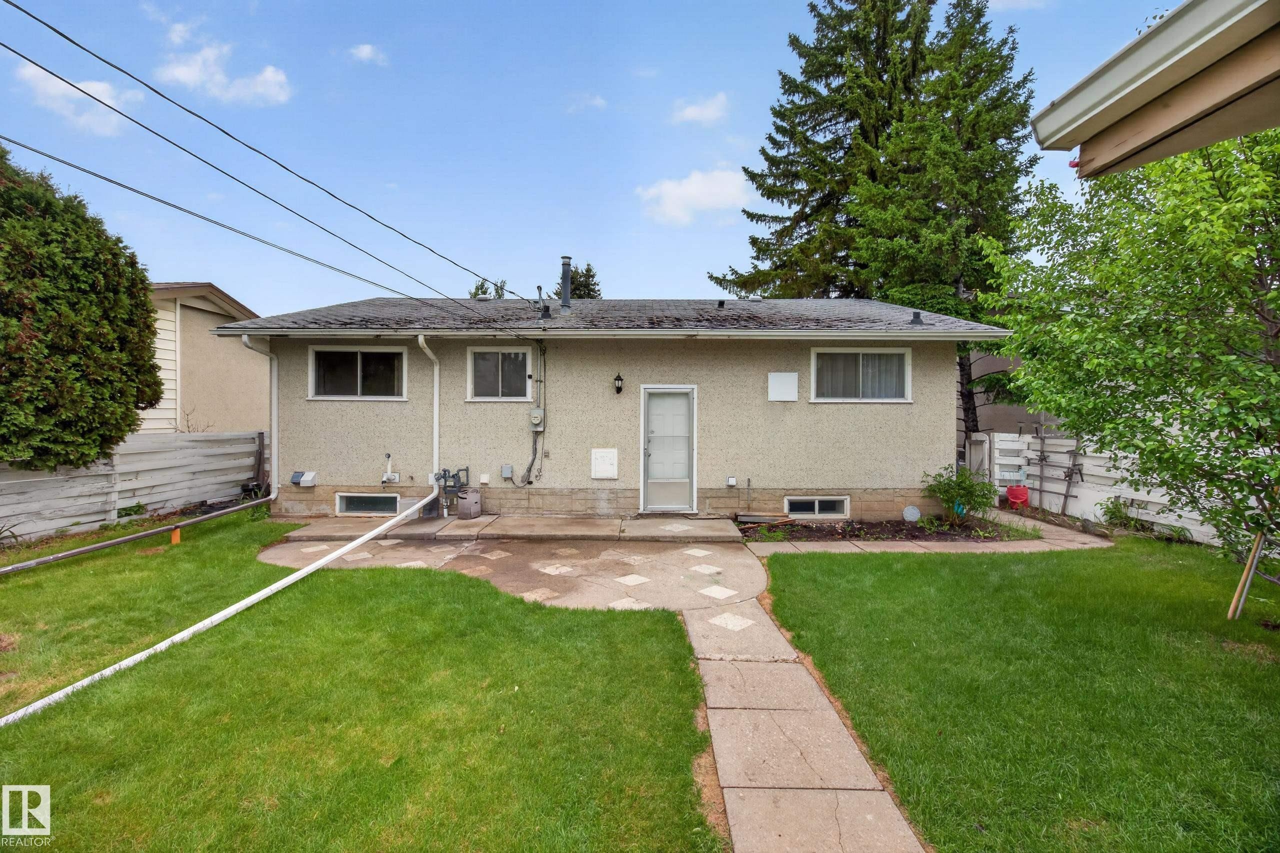 Expansive backyard featuring a manicured lawn, concrete patio, and stone paver pathway - 5216 104A Street, Edmonton, AB - Outdoor