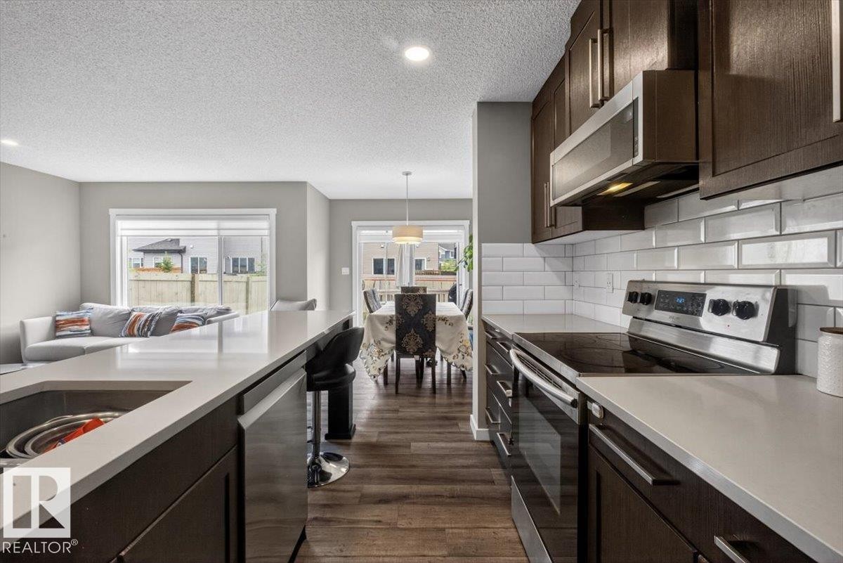 Kitchen featuring wood-finish cabinetry, stainless steel appliances, and light-toned countertops - 223 40A Avenue, Edmonton, AB - Indoor Photo Showing Kitchen With Upgraded Kitchen