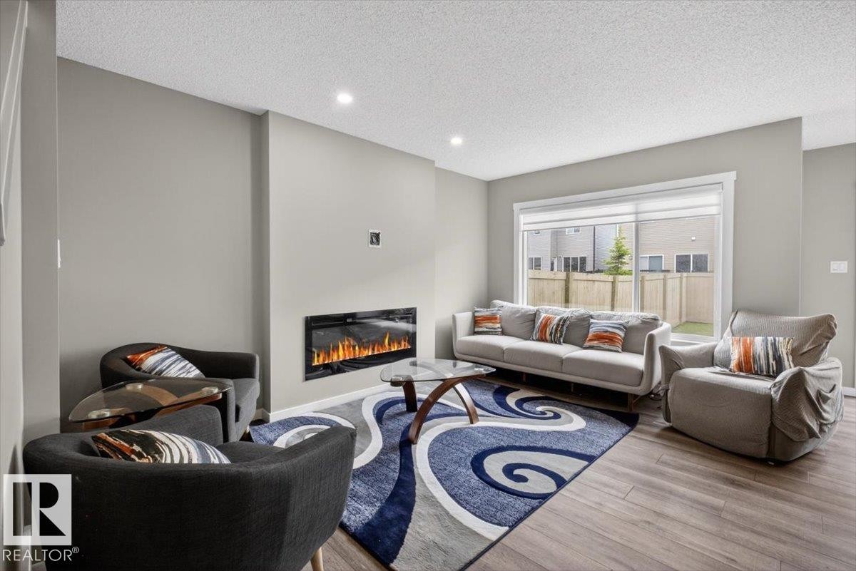 Open-concept living space featuring wood-finish flooring, recessed lighting, and a linear electric fireplace - 223 40A Avenue, Edmonton, AB - Indoor Photo Showing Living Room With Fireplace