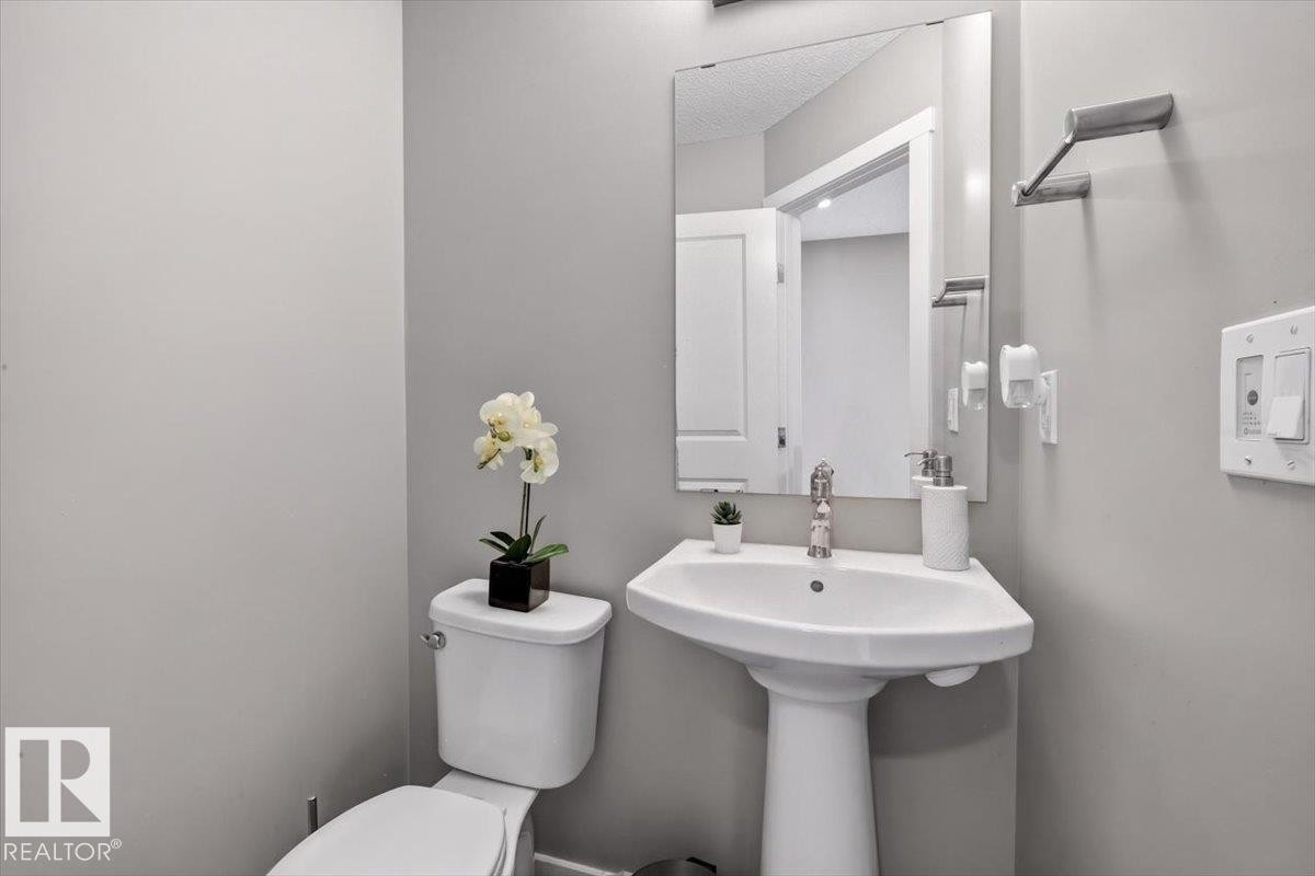 Pedestal sink with chrome faucet, mirror, and wall-mounted towel bar - 223 40A Avenue, Edmonton, AB - Indoor Photo Showing Bathroom