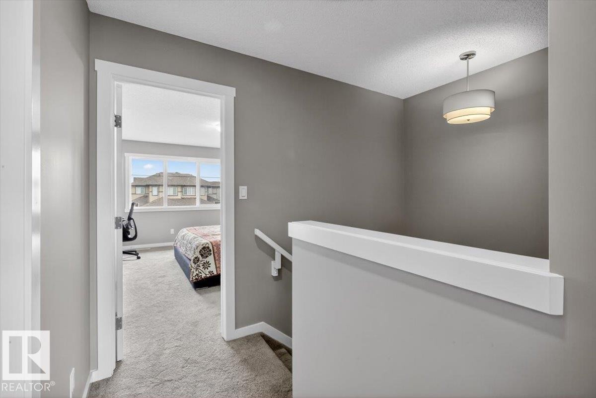 Carpeted hallway with painted walls, white trim, and a contemporary drum pendant light fixture - 223 40A Avenue, Edmonton, AB - Indoor Photo Showing Other Room