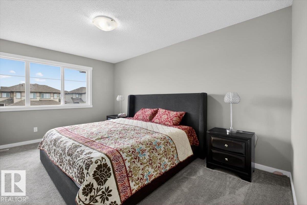 Bedroom featuring a multi-pane window, neutral wall paint, textured ceiling, and gray carpet flooring - 223 40A Avenue, Edmonton, AB - Indoor Photo Showing Bedroom
