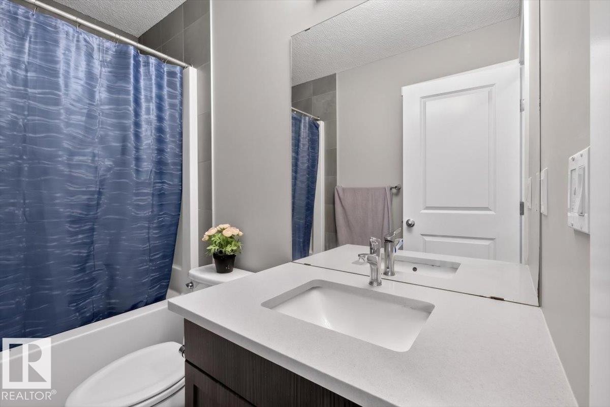 Bathroom featuring a vanity with a white countertop and integrated sink, chrome faucet, and dark wood-finish cabinetry - 223 40A Avenue, Edmonton, AB - Indoor Photo Showing Bathroom