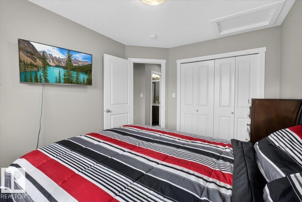 Recessed lighting illuminates this bedroom featuring a built-in closet with bi-fold doors, a mounted television, and a neutral wall palette - 223 40A Avenue, Edmonton, AB - Indoor Photo Showing Bedroom