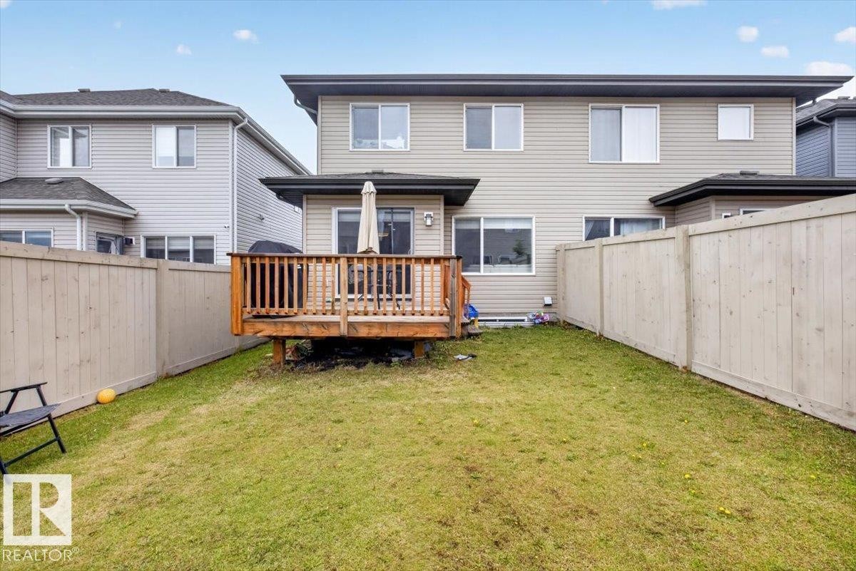Rear exterior featuring a spacious wood deck, light-toned siding, dark roofline, and multiple windows - 223 40A Avenue, Edmonton, AB - Outdoor With Exterior