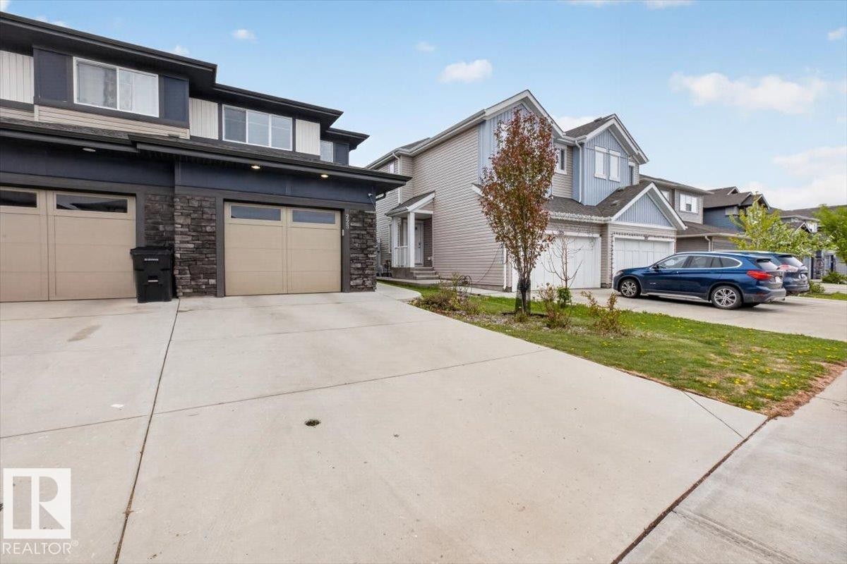 Modern townhouse with a stone and siding exterior, featuring two attached garages with frosted window panels and individual driveways - 223 40A Avenue, Edmonton, AB - Outdoor With Facade