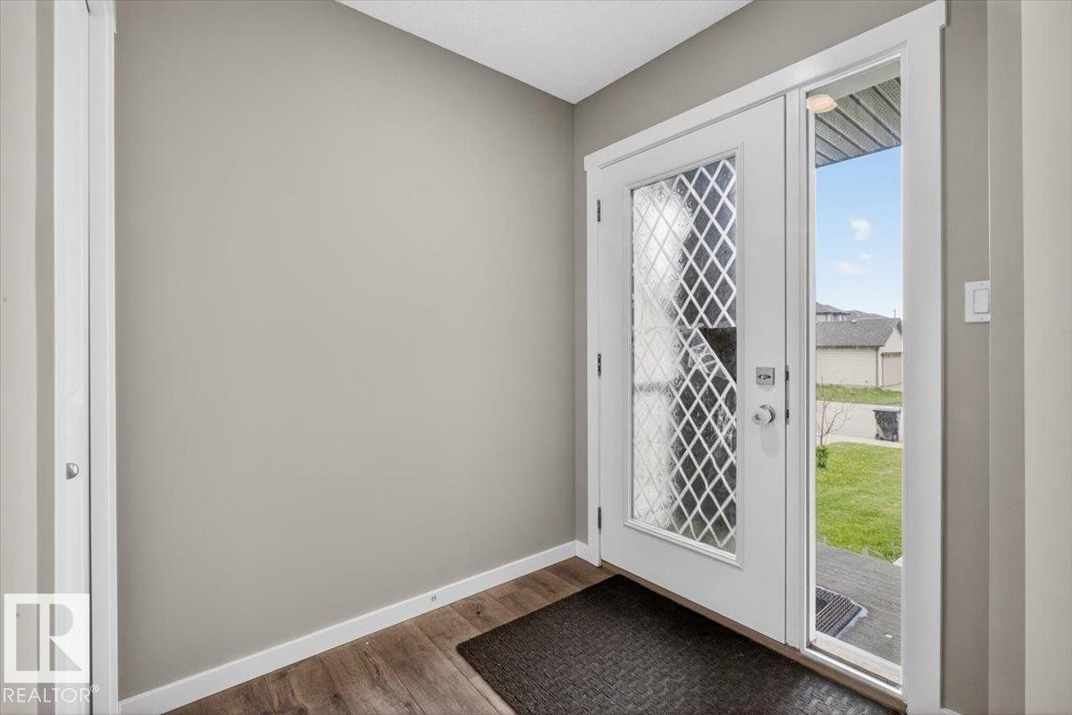 Entryway featuring a white door with decorative glass inserts, a full-length sidelight, wood-finish flooring, and light gray wall paint - 223 40A Avenue, Edmonton, AB - Indoor Photo Showing Other Room