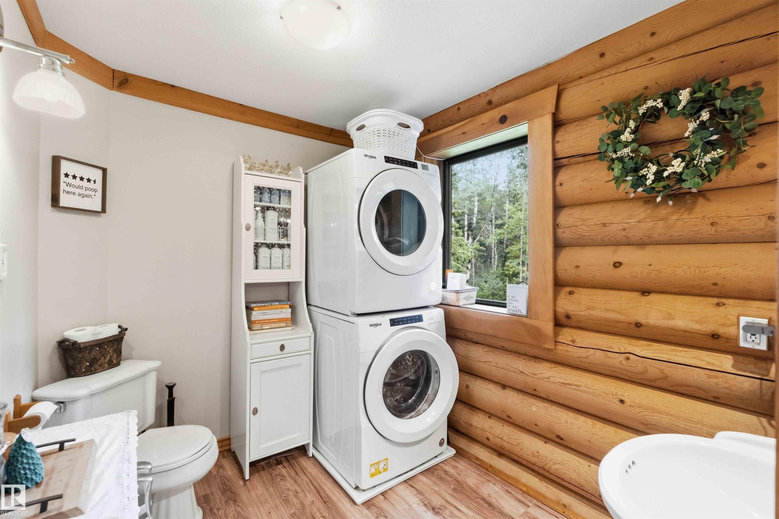 Laundry area featuring stacked appliances, log-style wall, wood-finish flooring, and a large window - #17 A 15031 Twp Road 462, Rural Wetaskiwin County, AB - Indoor Photo Showing Kitchen