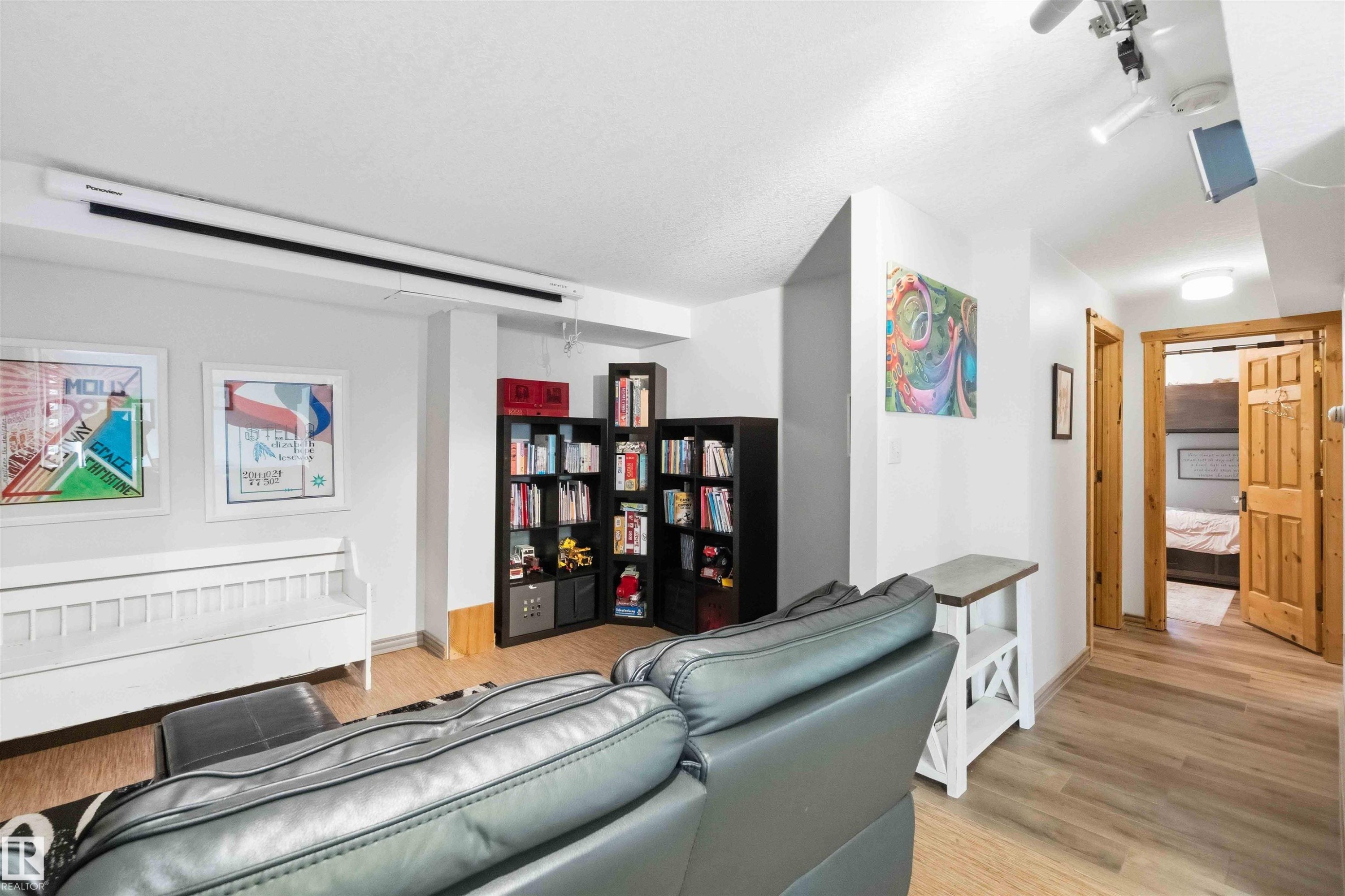 Recreational room featuring a ceiling-mounted projection screen, track lighting, and wood-finish flooring - #17 A 15031 Twp Road 462, Rural Wetaskiwin County, AB - Indoor With Fireplace