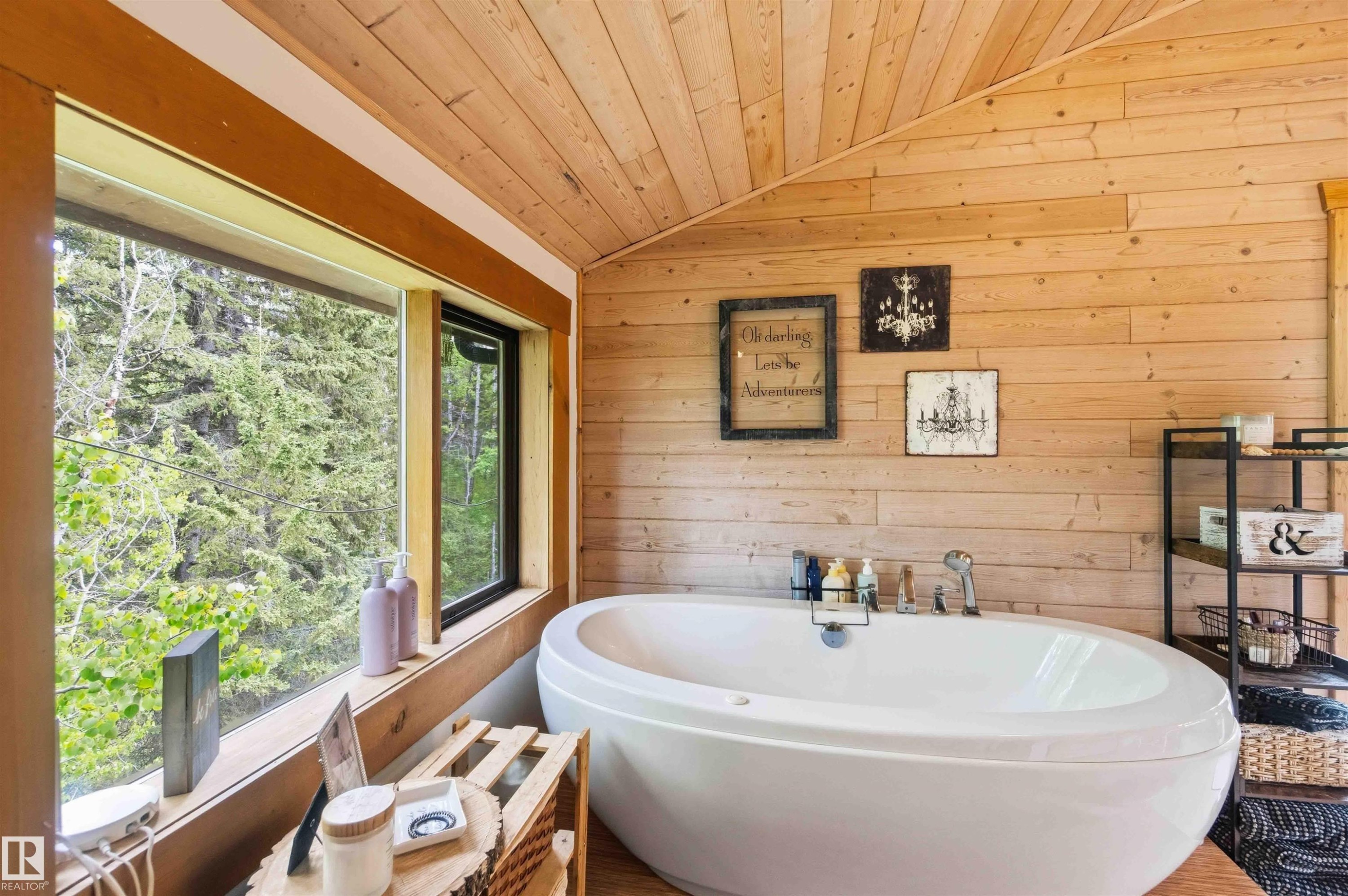 Freestanding soaking tub with floor-mounted fixtures, wood-paneled walls and ceiling, large picture window, and wood-finish flooring - #17 A 15031 Twp Road 462, Rural Wetaskiwin County, AB - With Deck Patio Veranda With Exterior