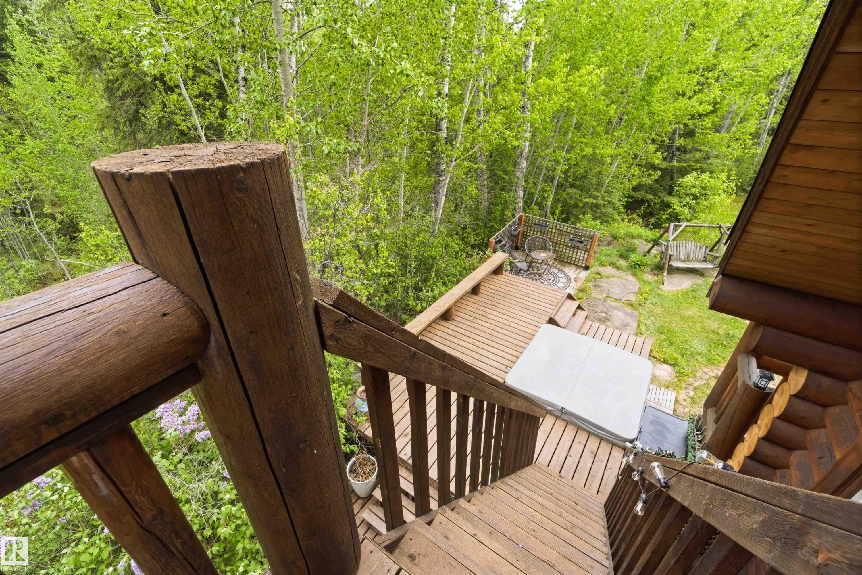 Multi-level wood deck featuring a spa, integrated wood stairs, log railing, and a stone patio with a fire pit - #17 A 15031 Twp Road 462, Rural Wetaskiwin County, AB - Outdoor