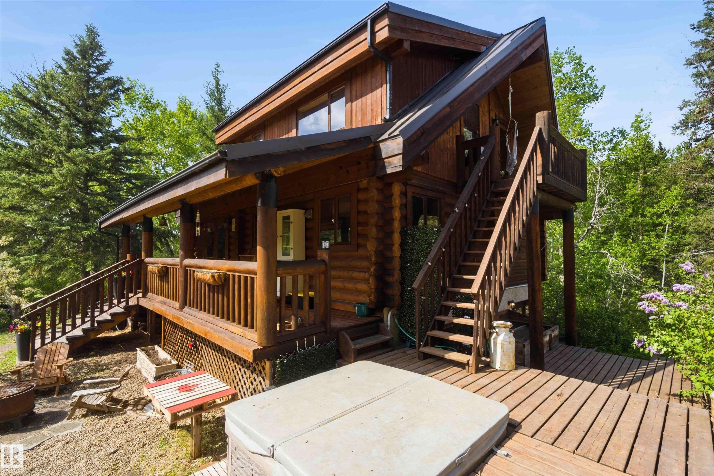 Log cabin exterior featuring a multi-level deck, covered porch, exterior stairway, and clear windows - #17 A 15031 Twp Road 462, Rural Wetaskiwin County, AB - Outdoor With Deck Patio Veranda