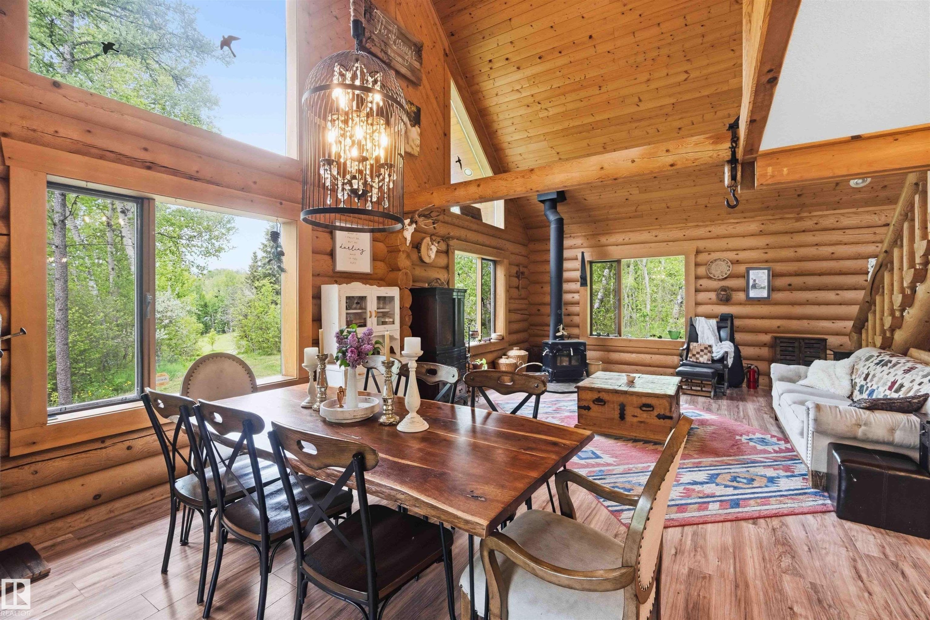 Open-concept dining and living area featuring extensive wood-finish flooring, exposed wood beam ceilings, and log wall construction - #17 A 15031 Twp Road 462, Rural Wetaskiwin County, AB - Indoor Photo Showing Dining Room