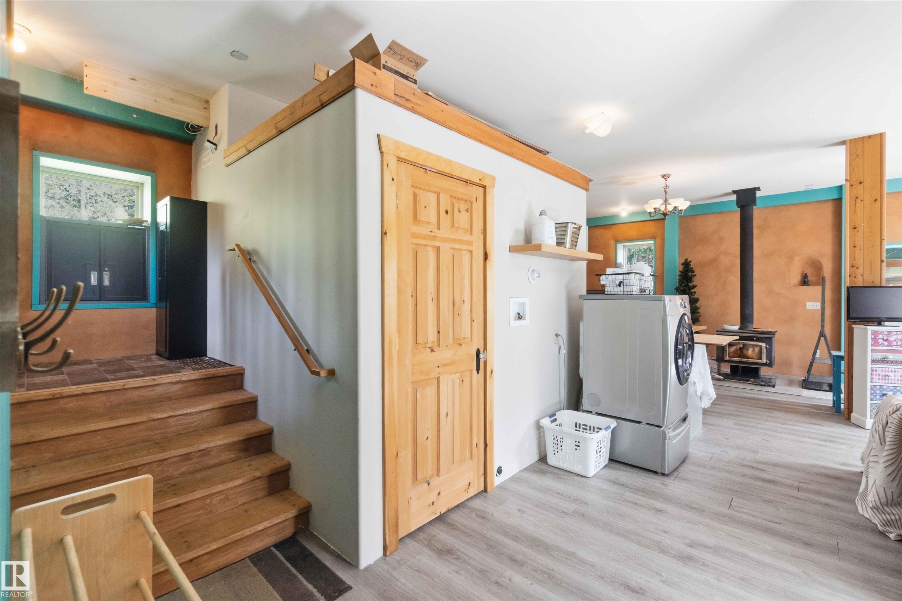 Wood-finish flooring throughout, featuring a wood-burning stove, built-in wooden staircase, and natural wood doors - #17 A 15031 Twp Road 462, Rural Wetaskiwin County, AB - Indoor Photo Showing Other Room