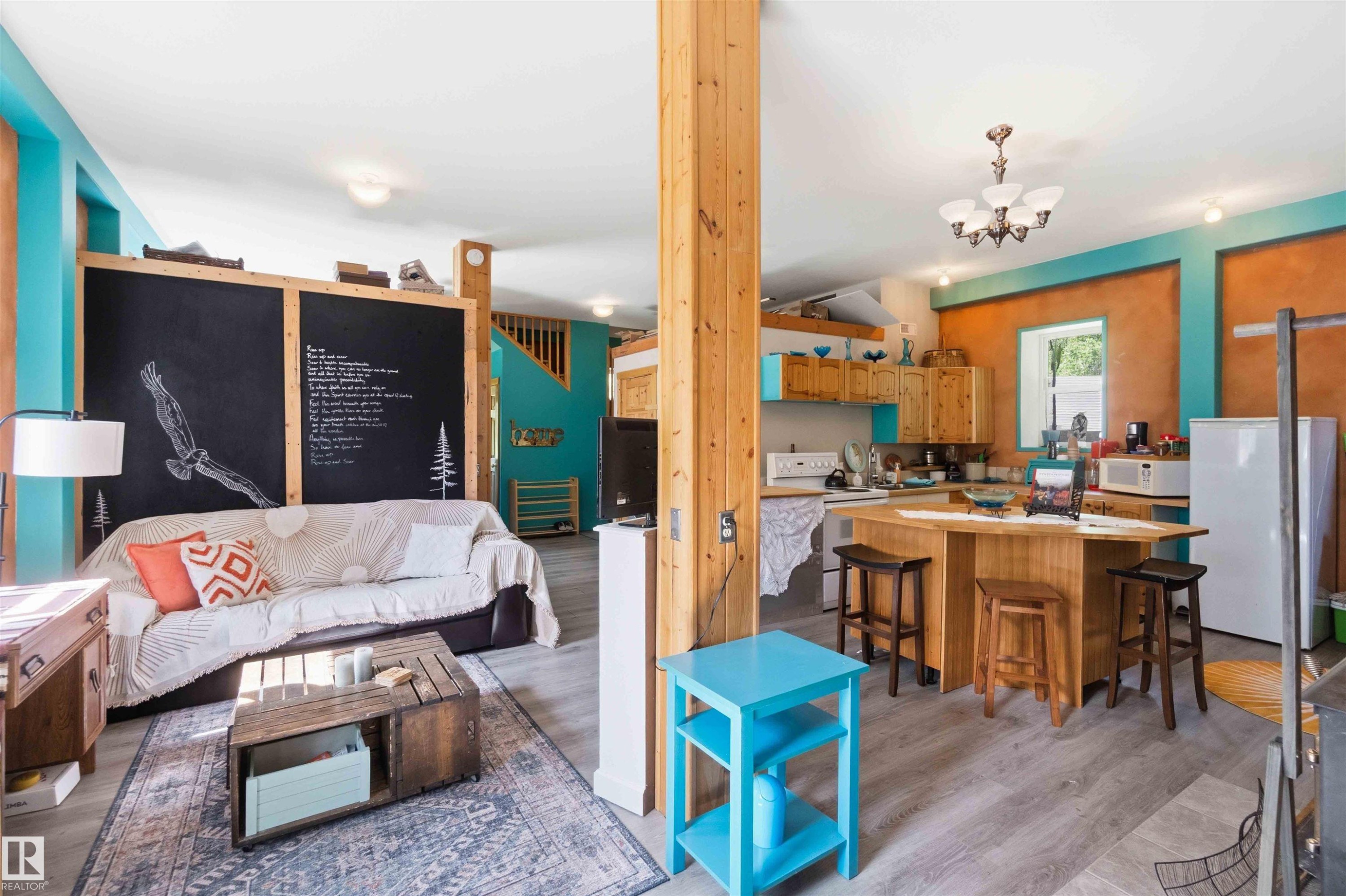 Open-concept living space featuring wood-finish flooring, exposed wood beams, and a combination of turquoise and terracotta wall finishes - #17 A 15031 Twp Road 462, Rural Wetaskiwin County, AB - Indoor