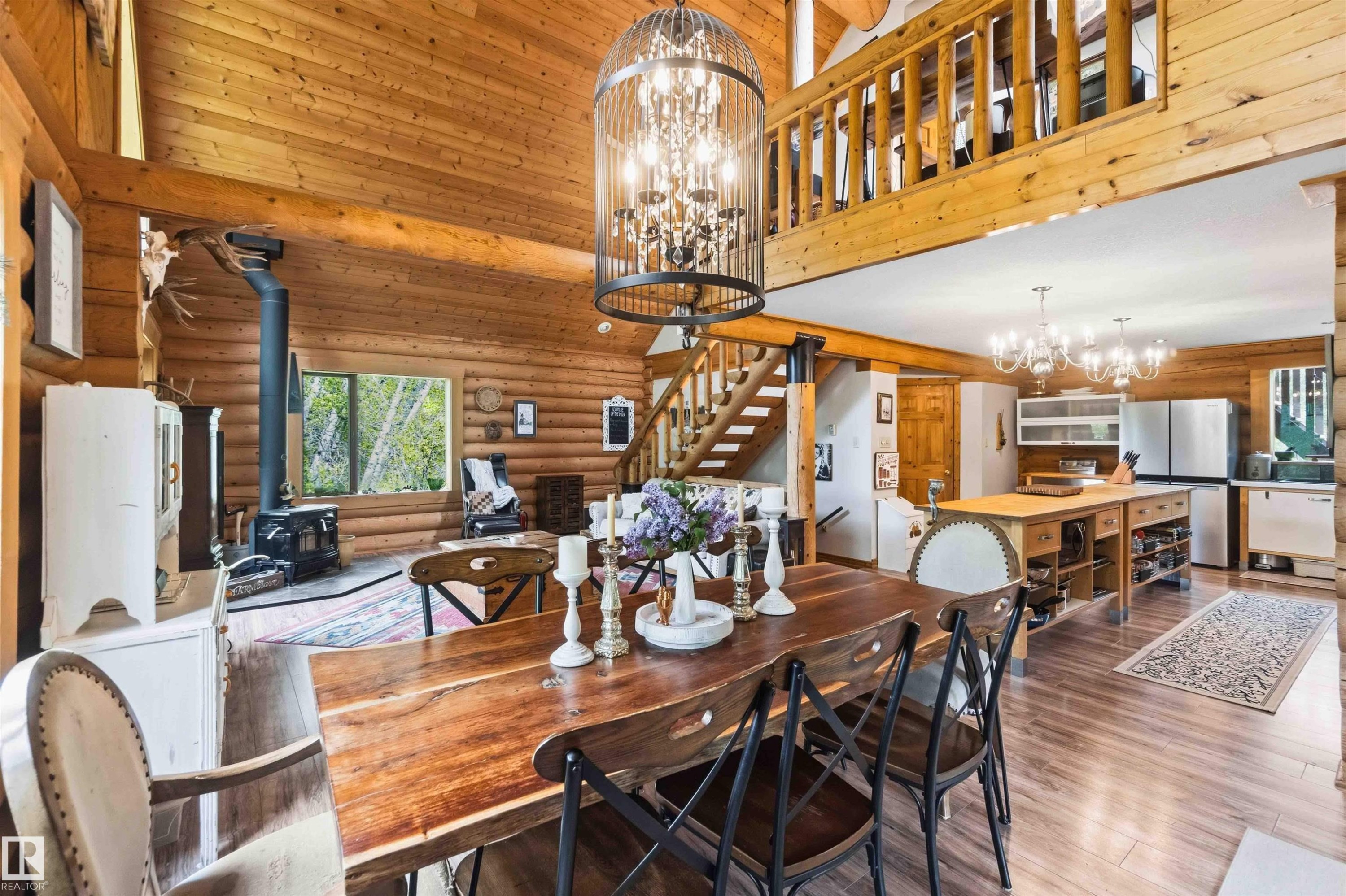 Open-concept main level featuring extensive log construction, wood-finish flooring, and a second-story loft with log railing - #17 A 15031 Twp Road 462, Rural Wetaskiwin County, AB - Indoor