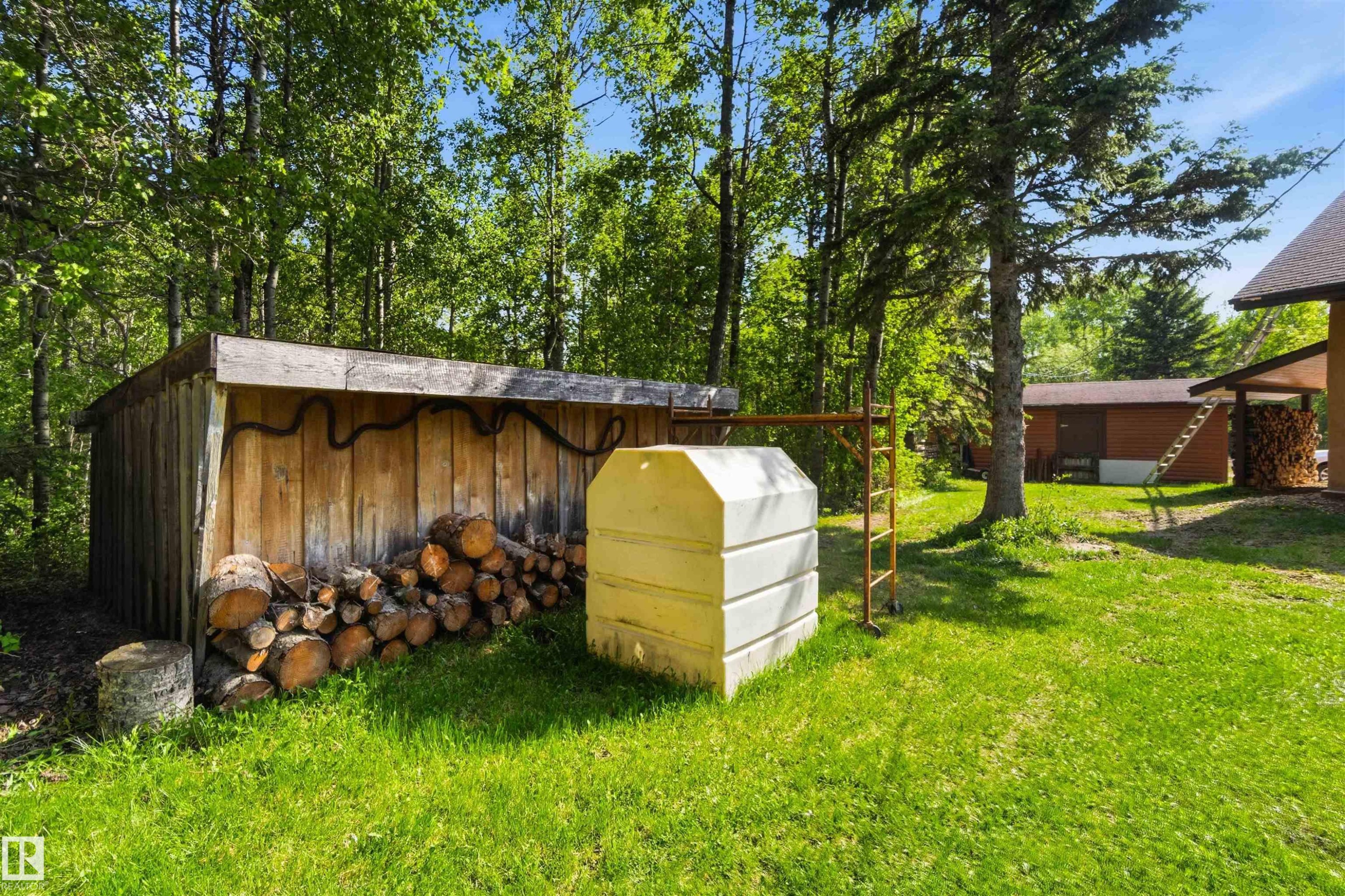 Rustic wood-sided storage shed with a lean-to roof, positioned on a grassy lawn - #17 A 15031 Twp Road 462, Rural Wetaskiwin County, AB - Outdoor With Exterior