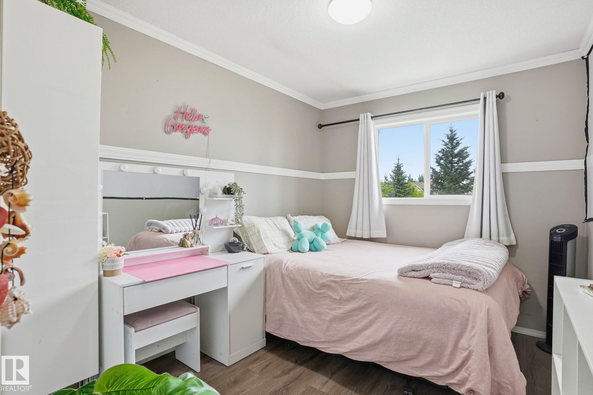 Bright bedroom featuring a large window, crown molding, and wood-finish flooring - 164 150 Edwards Drive, Edmonton, AB - Indoor Photo Showing Bedroom