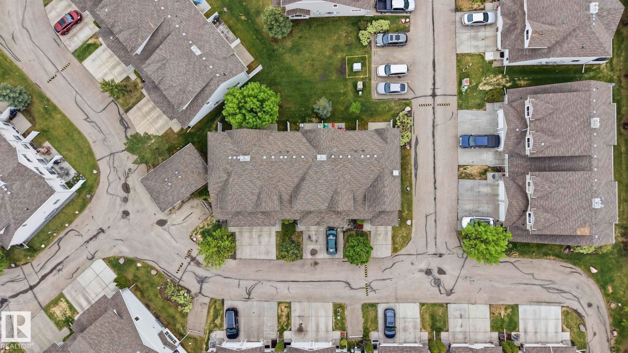 Aerial perspective showcasing a multi-unit property with private driveways and adjacent street access - 164 150 Edwards Drive, Edmonton, AB - With View
