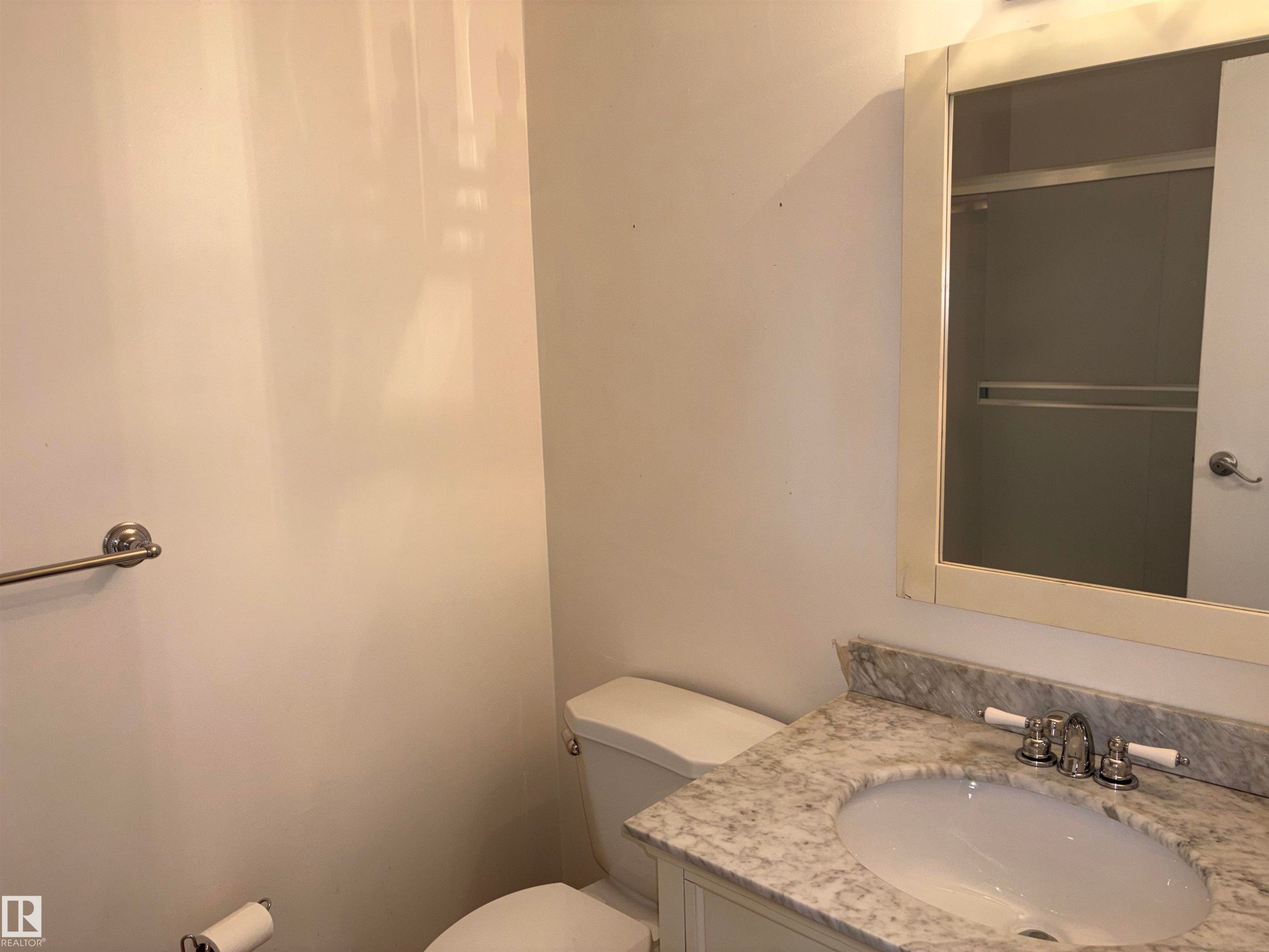 Bathroom vanity with an oval undermount sink, a polished chrome faucet with white handles, and a light-colored stone countertop - 167 Ridgewood, St. Albert, AB - Indoor Photo Showing Bathroom