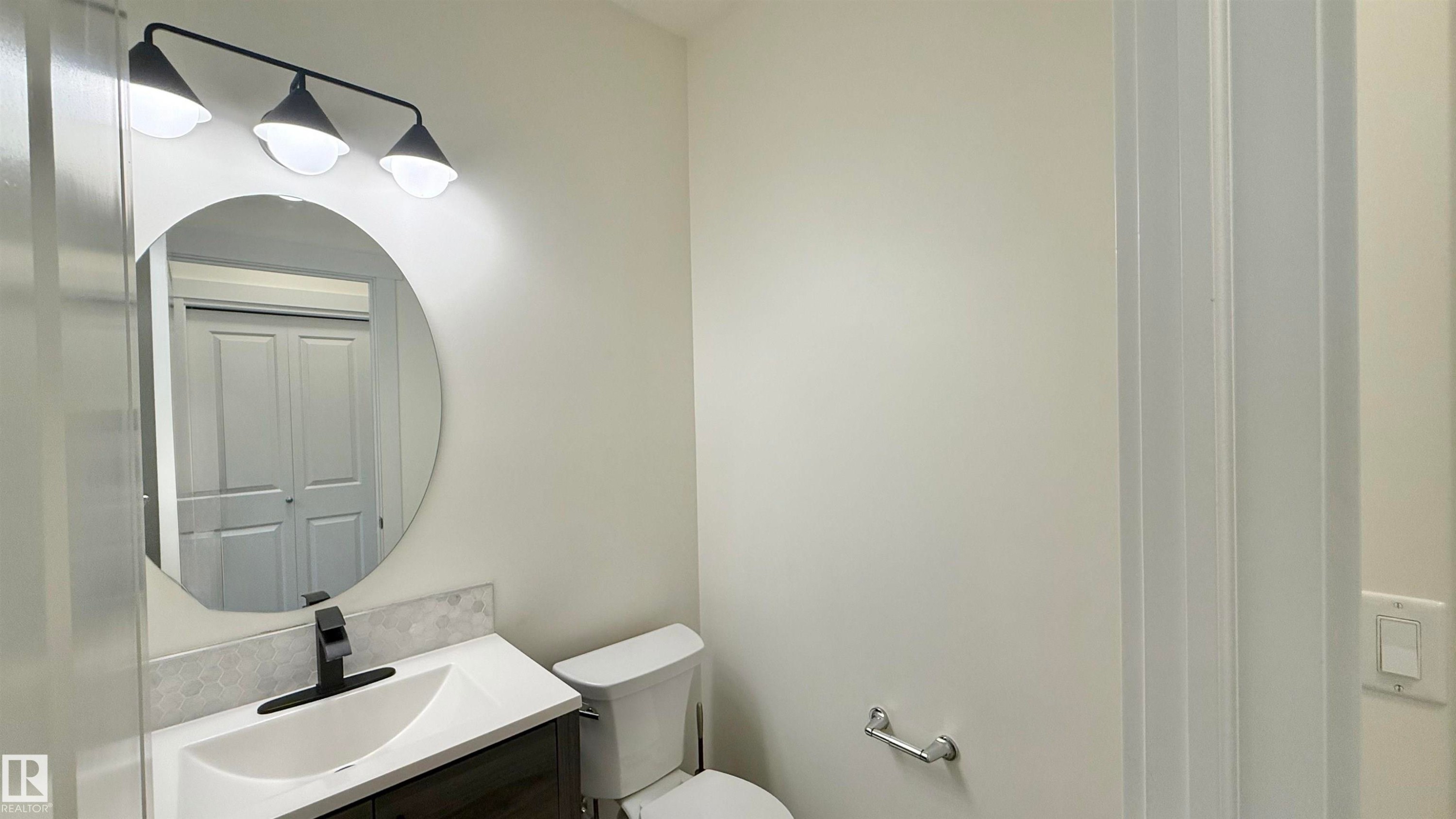 Bathroom featuring a white vanity with an integrated sink, a dark wood-finish cabinet, and a black faucet - 3962 Claxton Loop, Edmonton, AB - Indoor Photo Showing Bathroom