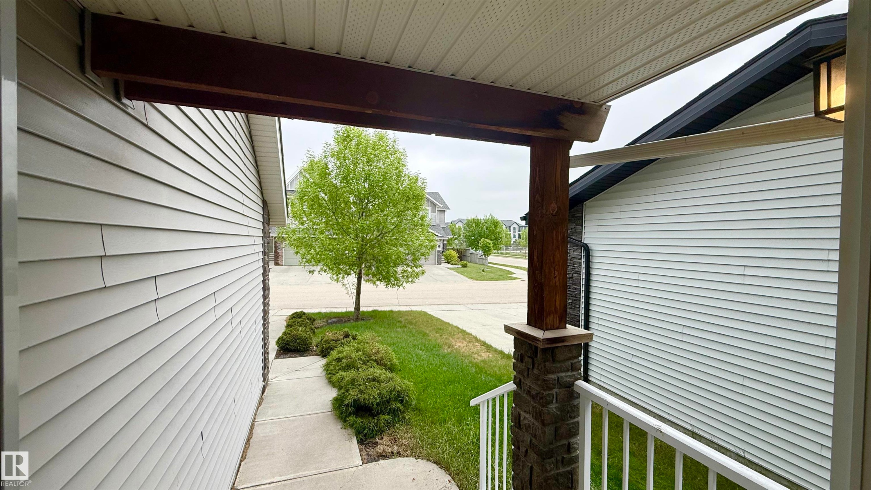 Covered front porch featuring a stone-clad post, wood beam accents, and white railings - 3962 Claxton Loop, Edmonton, AB - Outdoor With Deck Patio Veranda With Exterior
