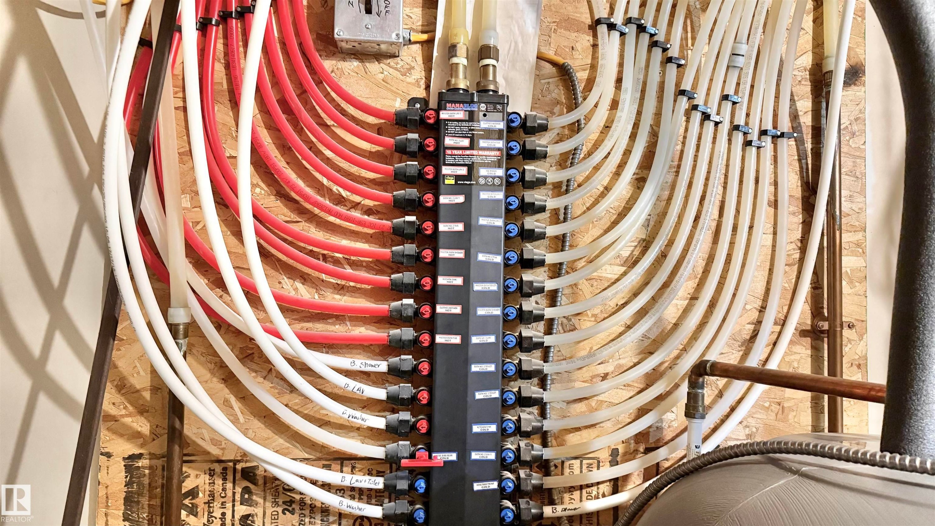 Radiant heating manifold system featuring multiple PEX lines, a central distribution panel, and integrated shut-off valves - 3962 Claxton Loop, Edmonton, AB - Indoor