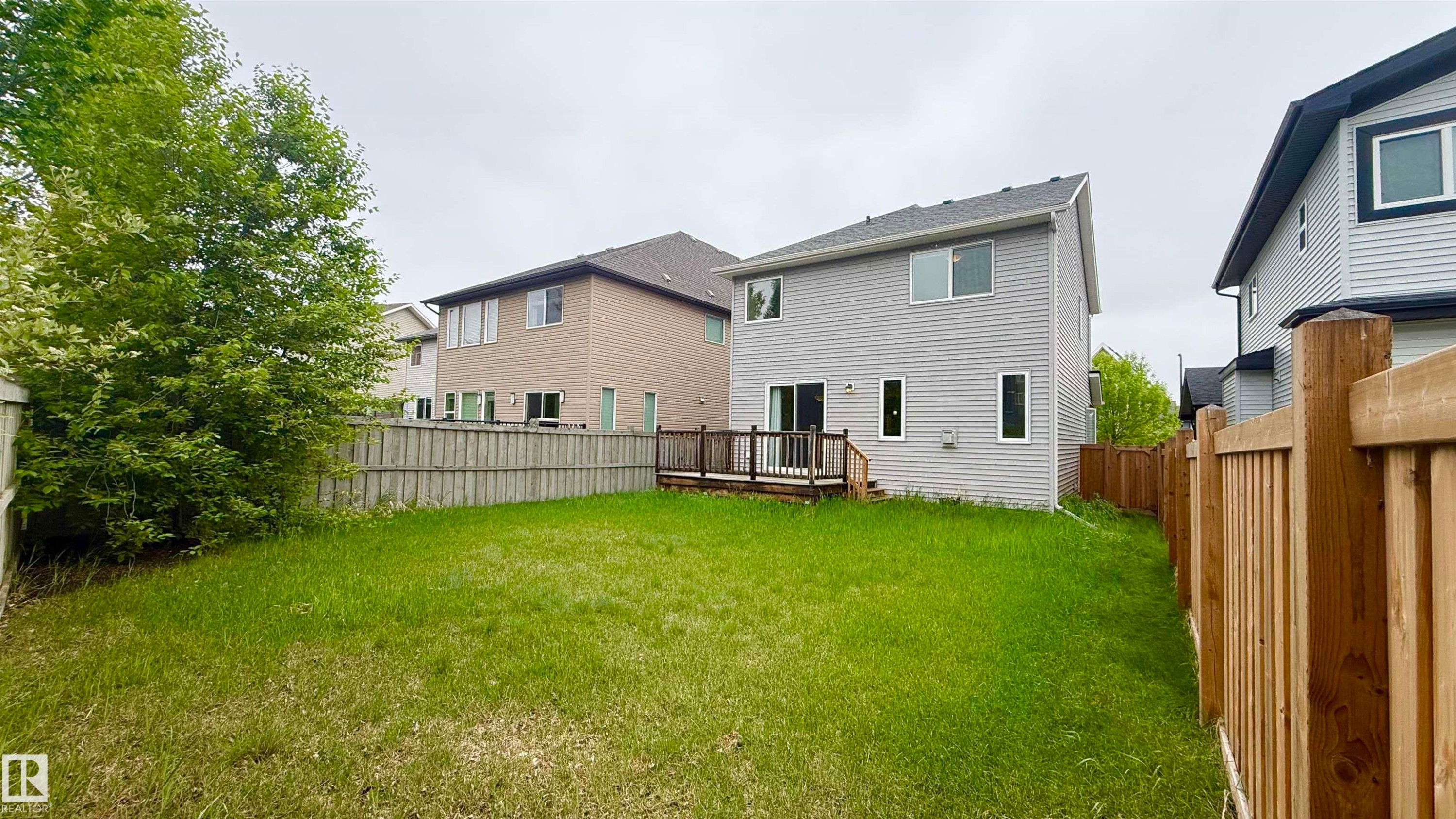Expansive backyard featuring a wood-finish privacy fence and a composite deck with railings - 3962 Claxton Loop, Edmonton, AB - Outdoor With Exterior
